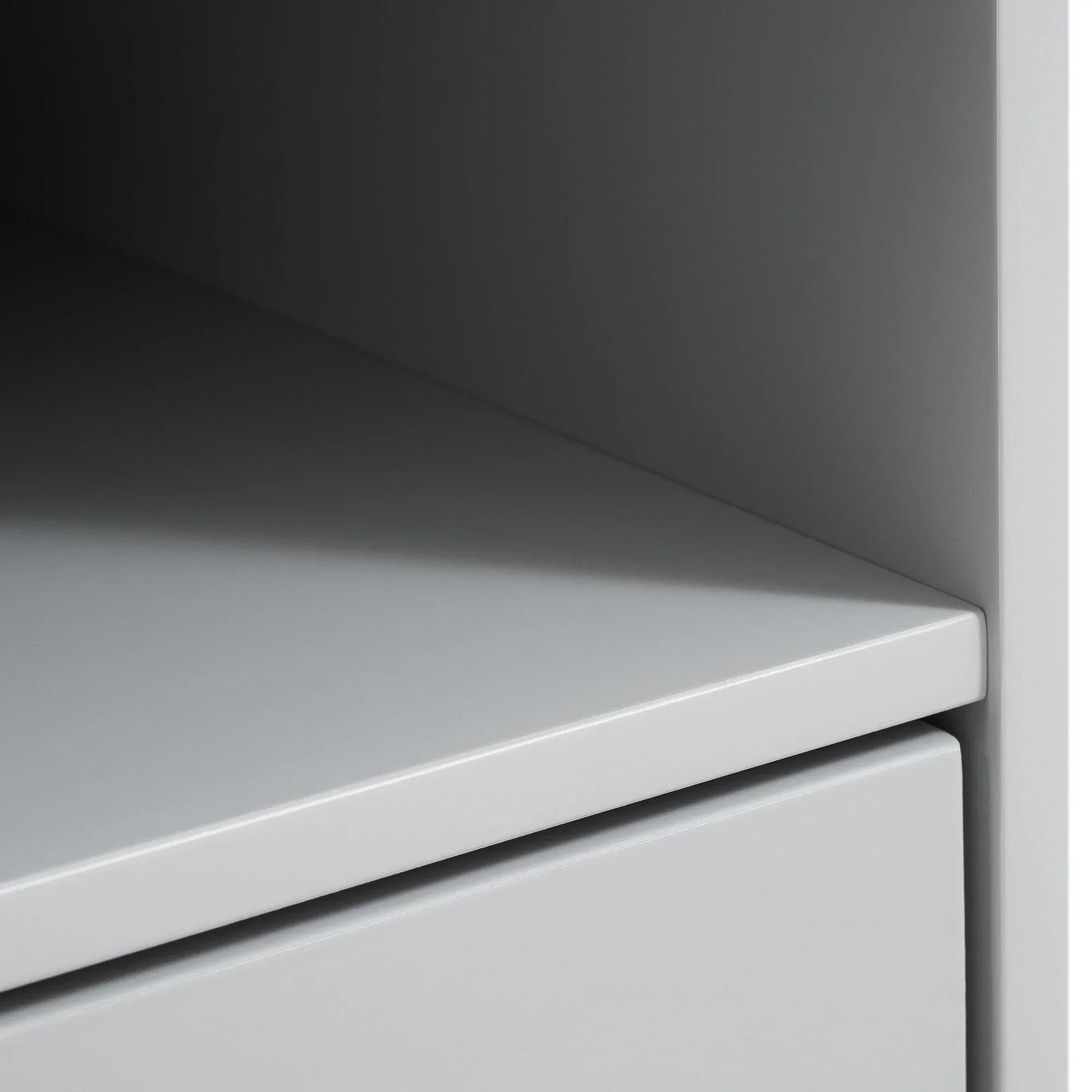 Close-up of grey desk corner showing smooth surface and drawer detail
