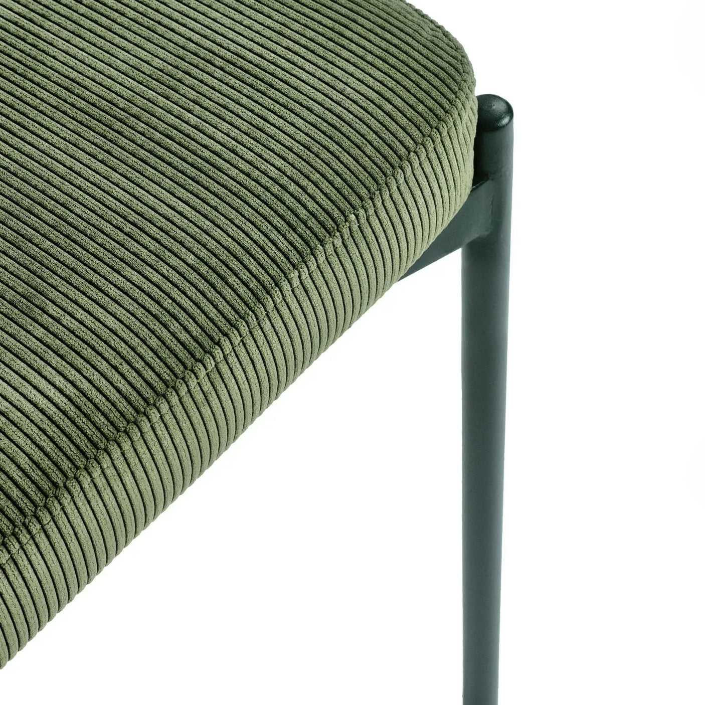 Green corduroy dining chair close up showing textured fabric and black metal leg detail