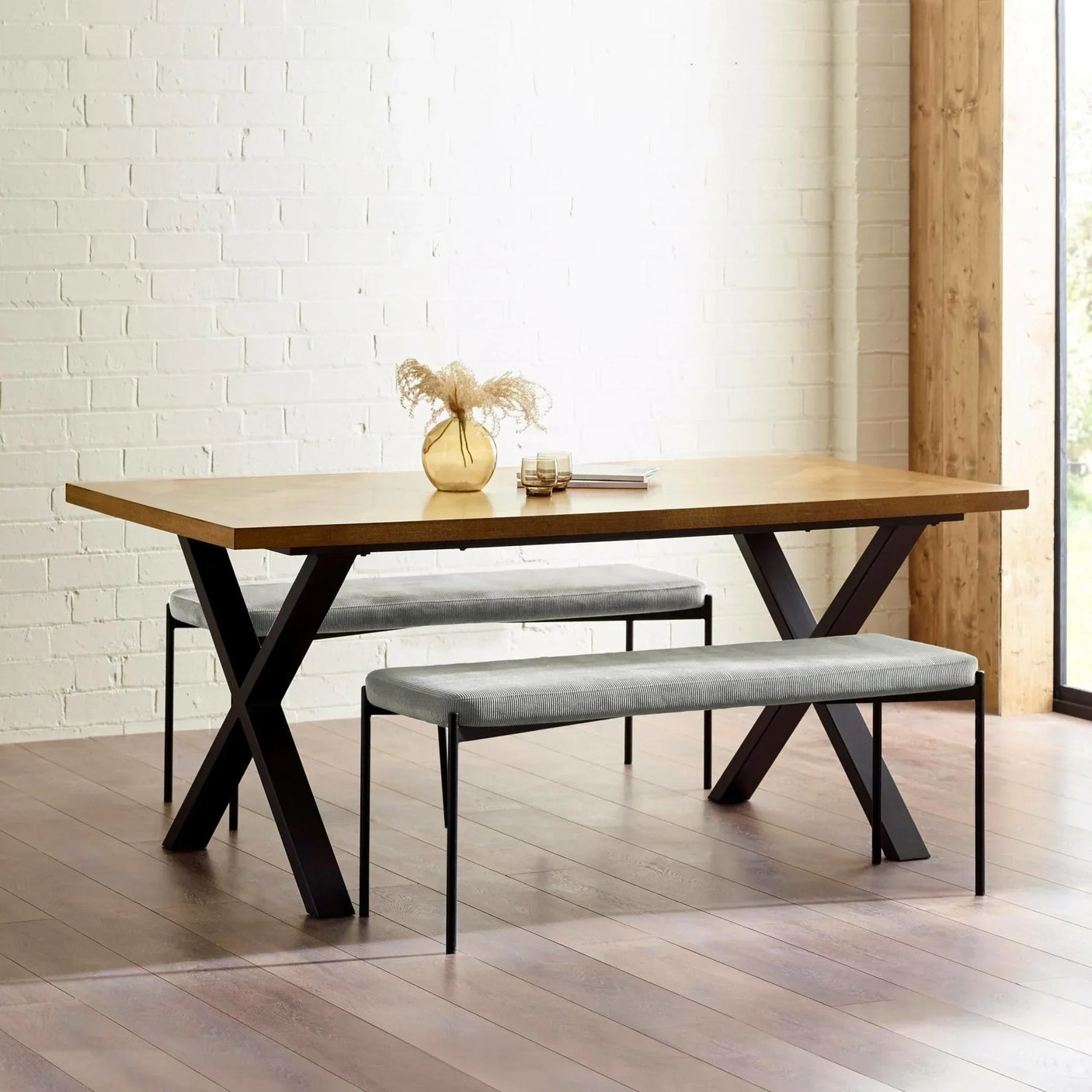 Wood dining table with black metal legs and two grey upholstered benches in modern room