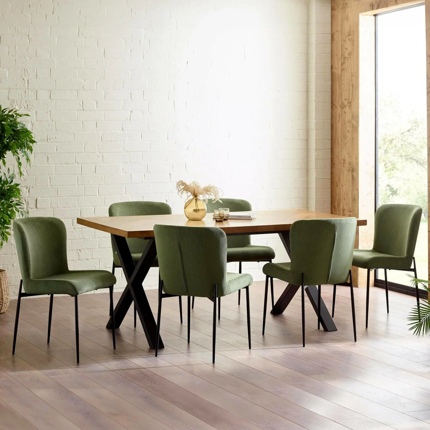 Oak dining table with green upholstered chairs in bright room with wooden floor