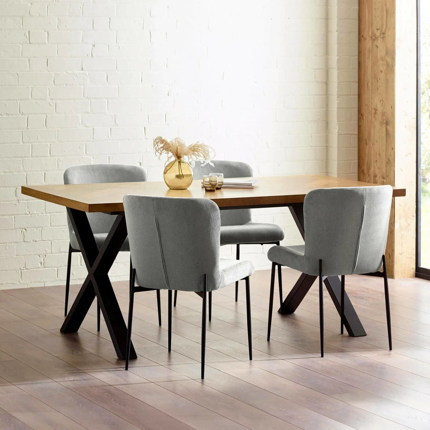 Oak dining table with black metal legs and four light grey upholstered chairs in modern room