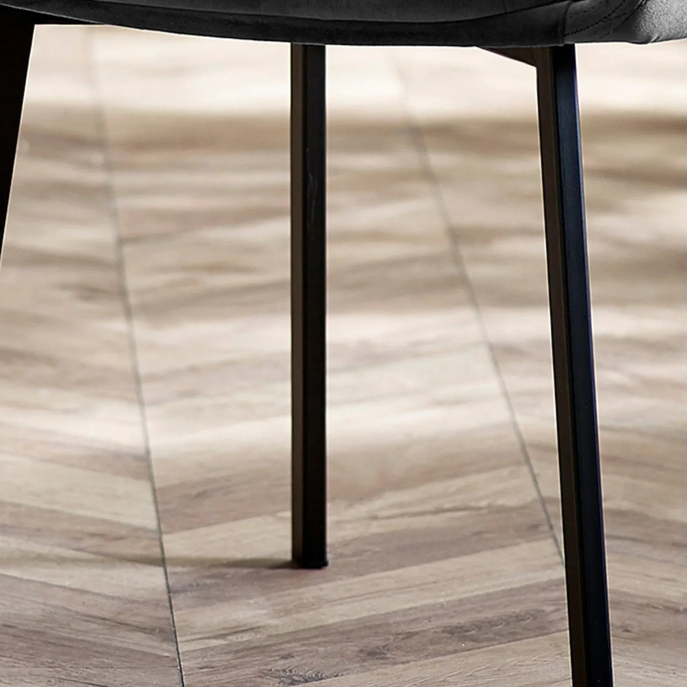Black metal dining chair legs on light wood chevron floor