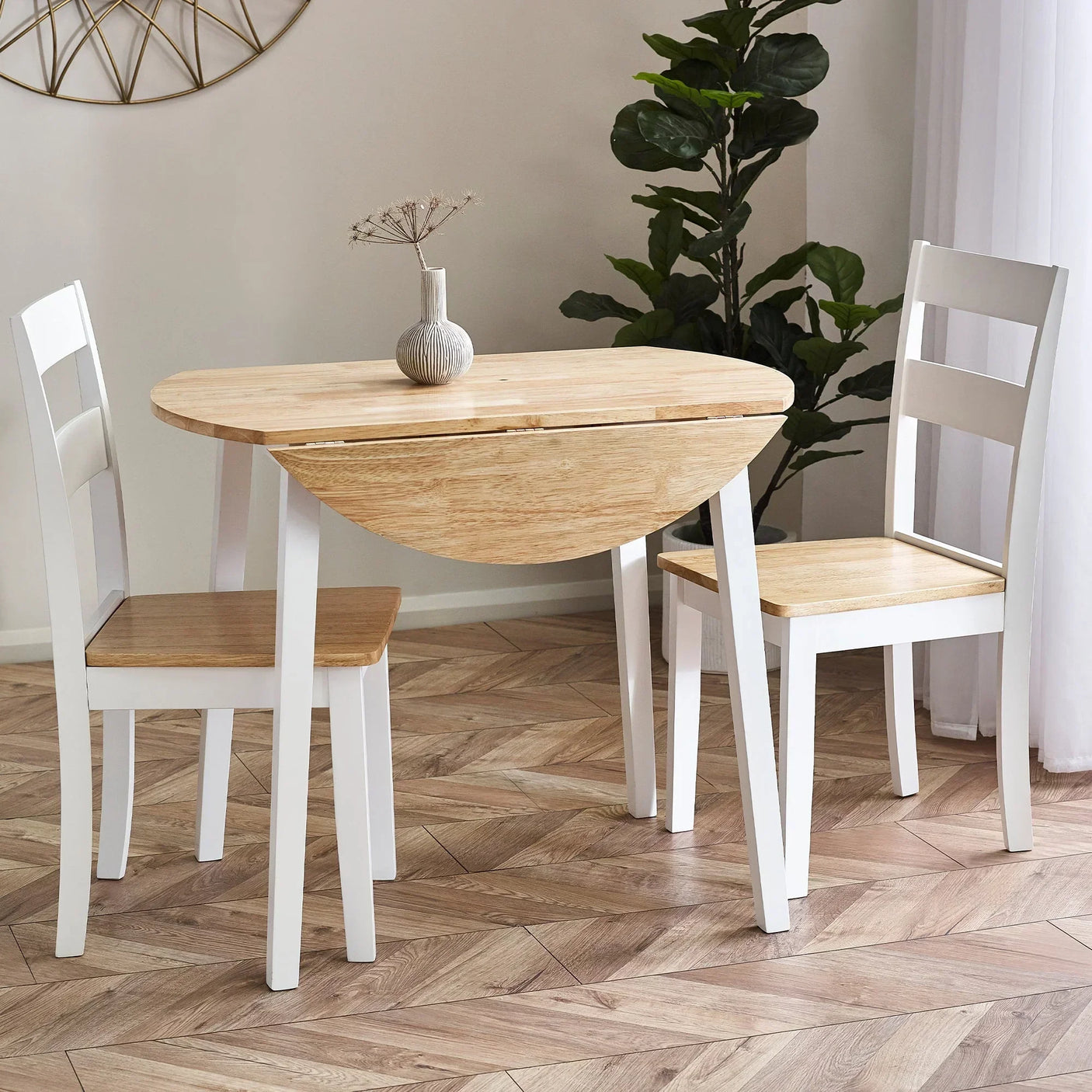 Round drop leaf dining table with two white chairs, wood top, set in bright dining room