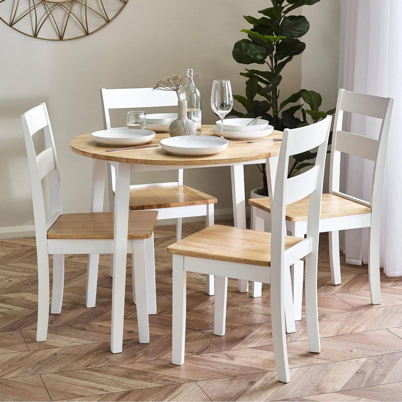 round drop leaf dining table with four wooden chairs set for meal in bright room