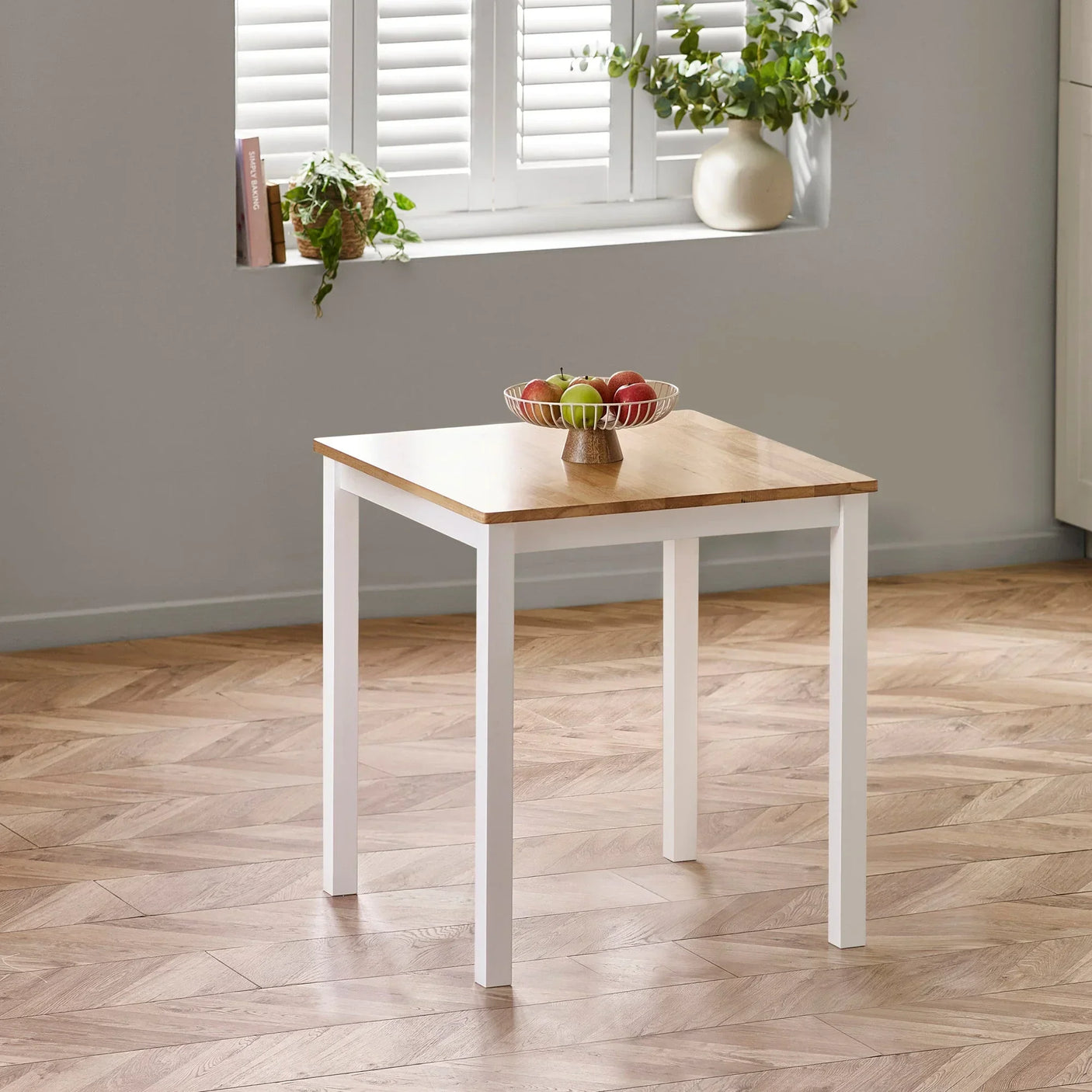 Square dining table with wood top and white legs, styled with fruit bowl in modern kitchen