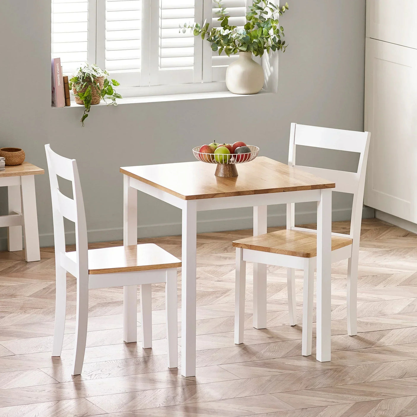 Two seater wooden dining table set with white chairs in bright kitchen corner