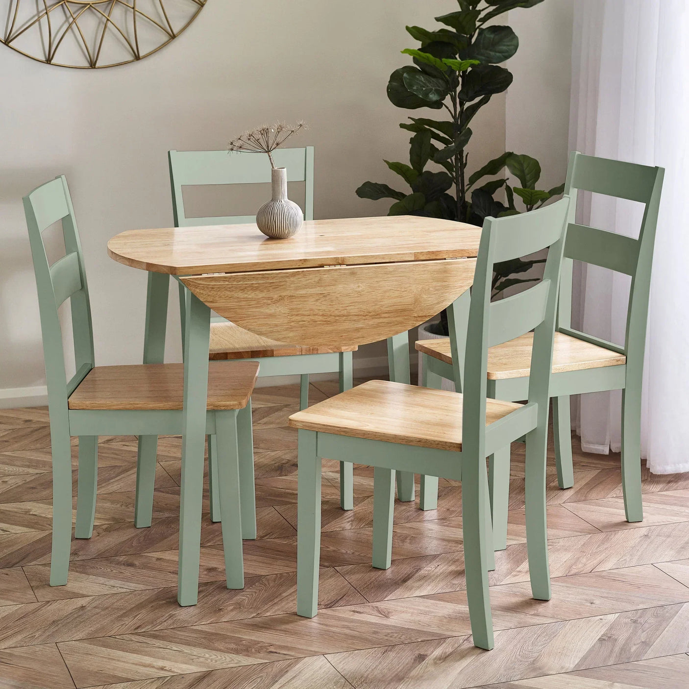 Light wood dining table with sage green legs and four matching chairs in modern room