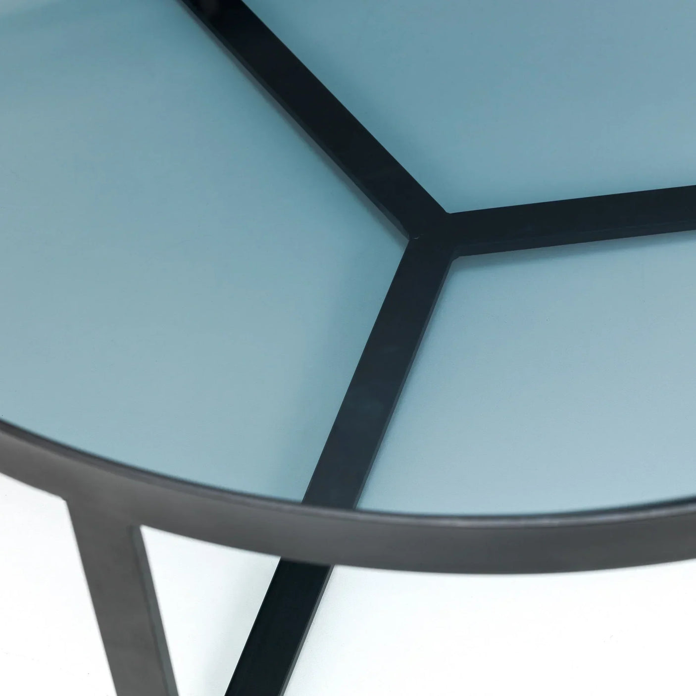 Detail of smoked glass coffee table top with black metal frame and intersecting support