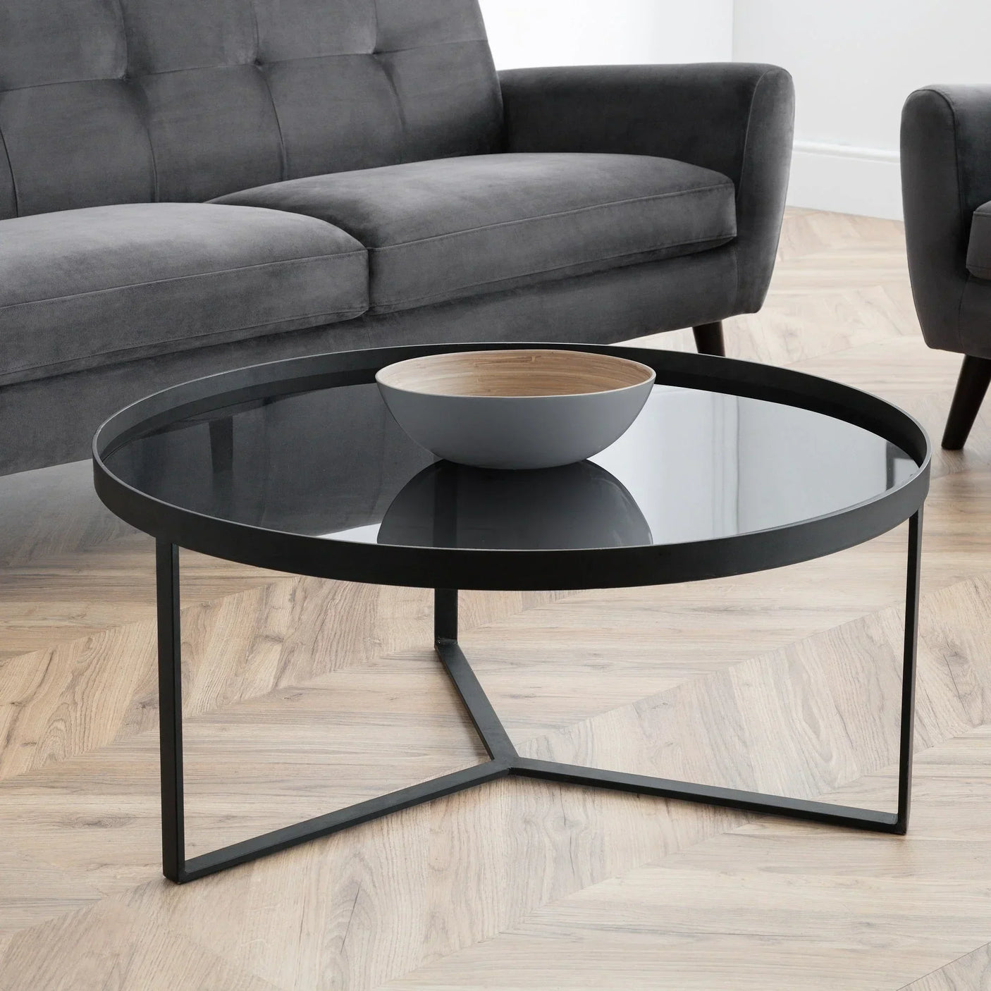 Round smoked glass coffee table with black metal frame in modern living room