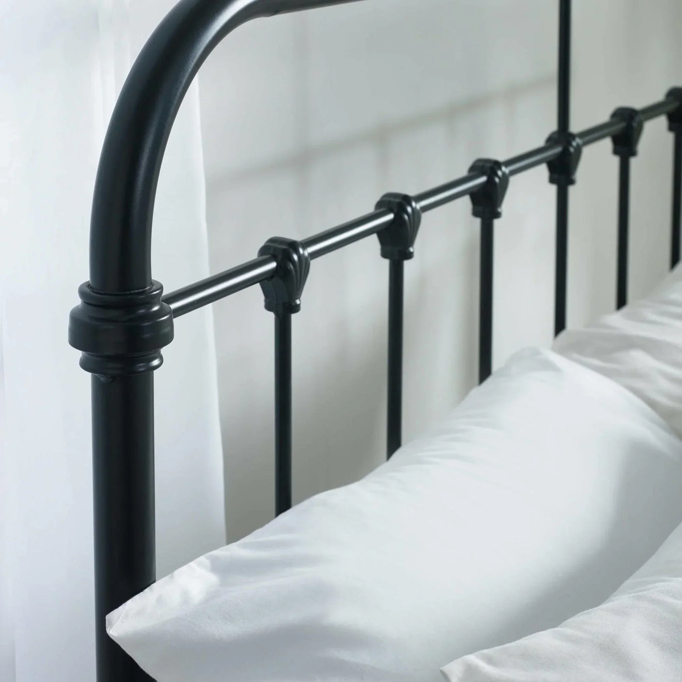 Black metal bed frame headboard with vertical bars and white bedding