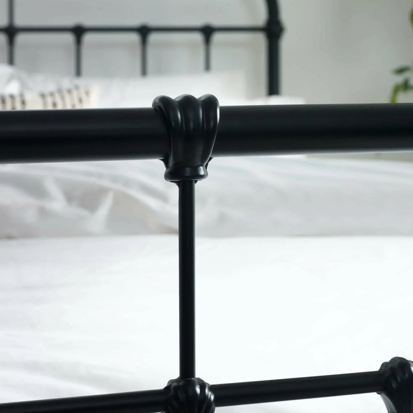 Black metal bed frame footboard with decorative detail in bright bedroom setting