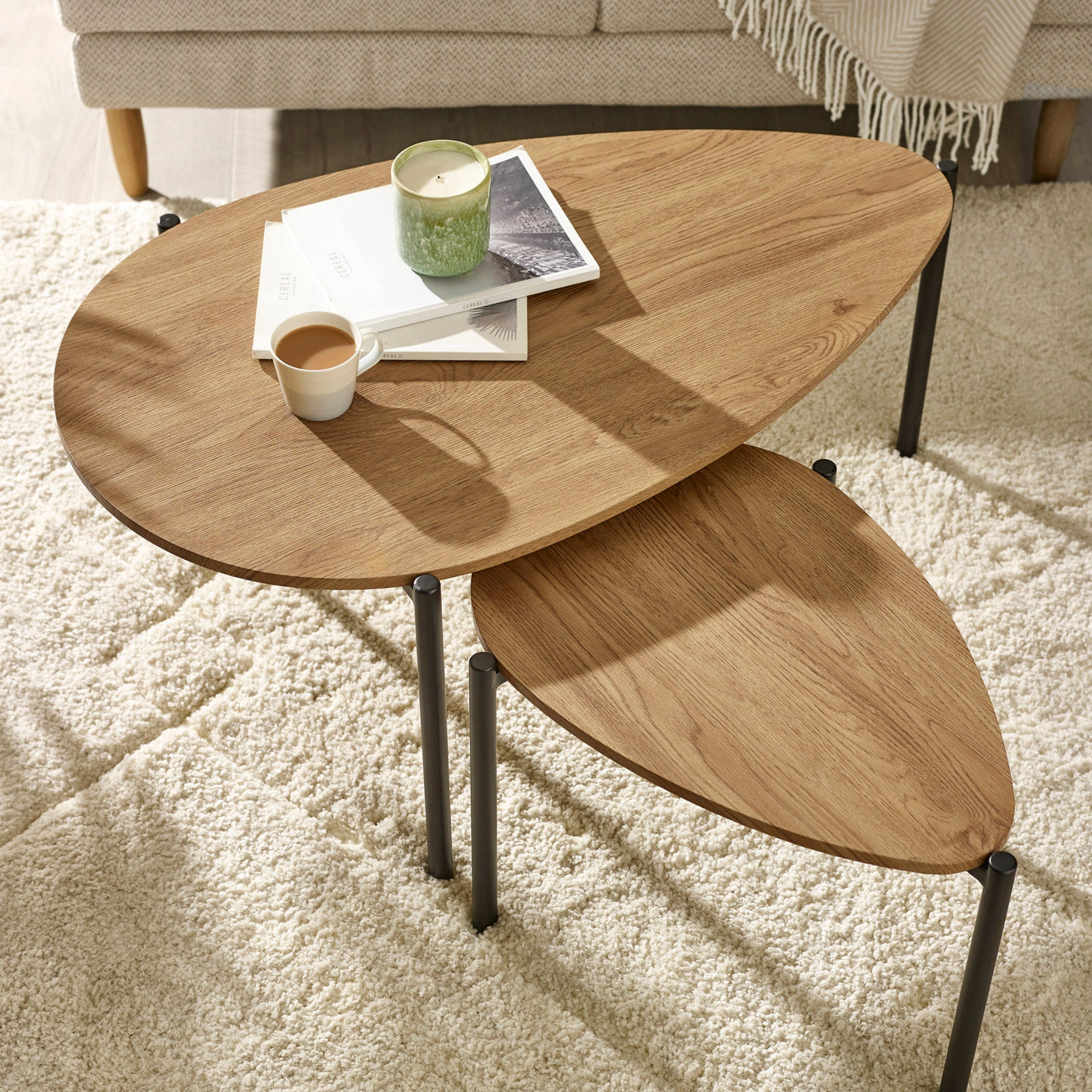 Close side angle of light oak nesting tables partially overlapped with black metal legs visible.