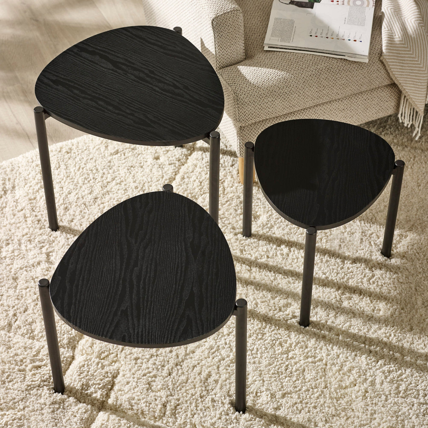 Single black teardrop nesting side table shown on white background with visible wood grain and black legs.