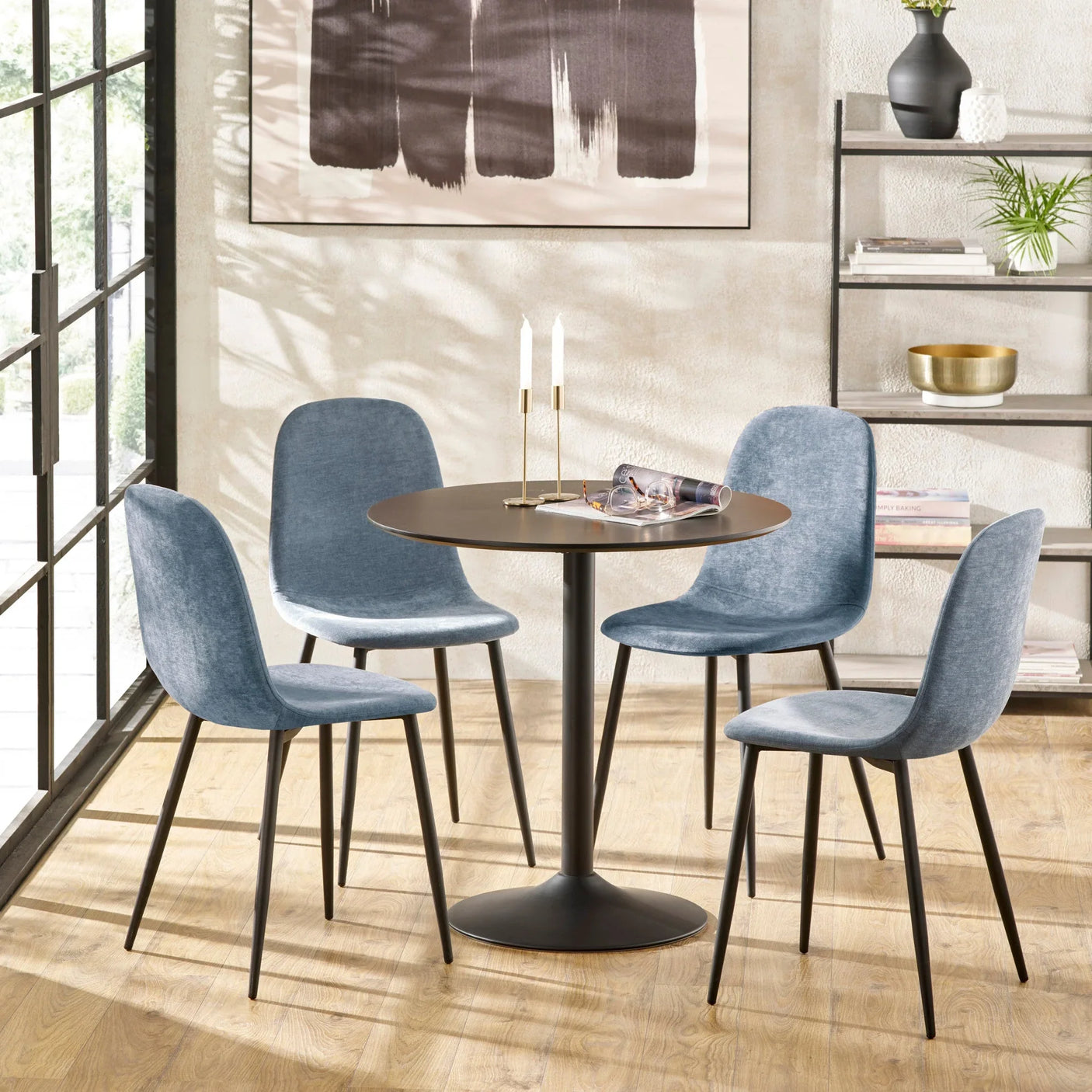 Round dining table set with four blue fabric chairs in modern dining room