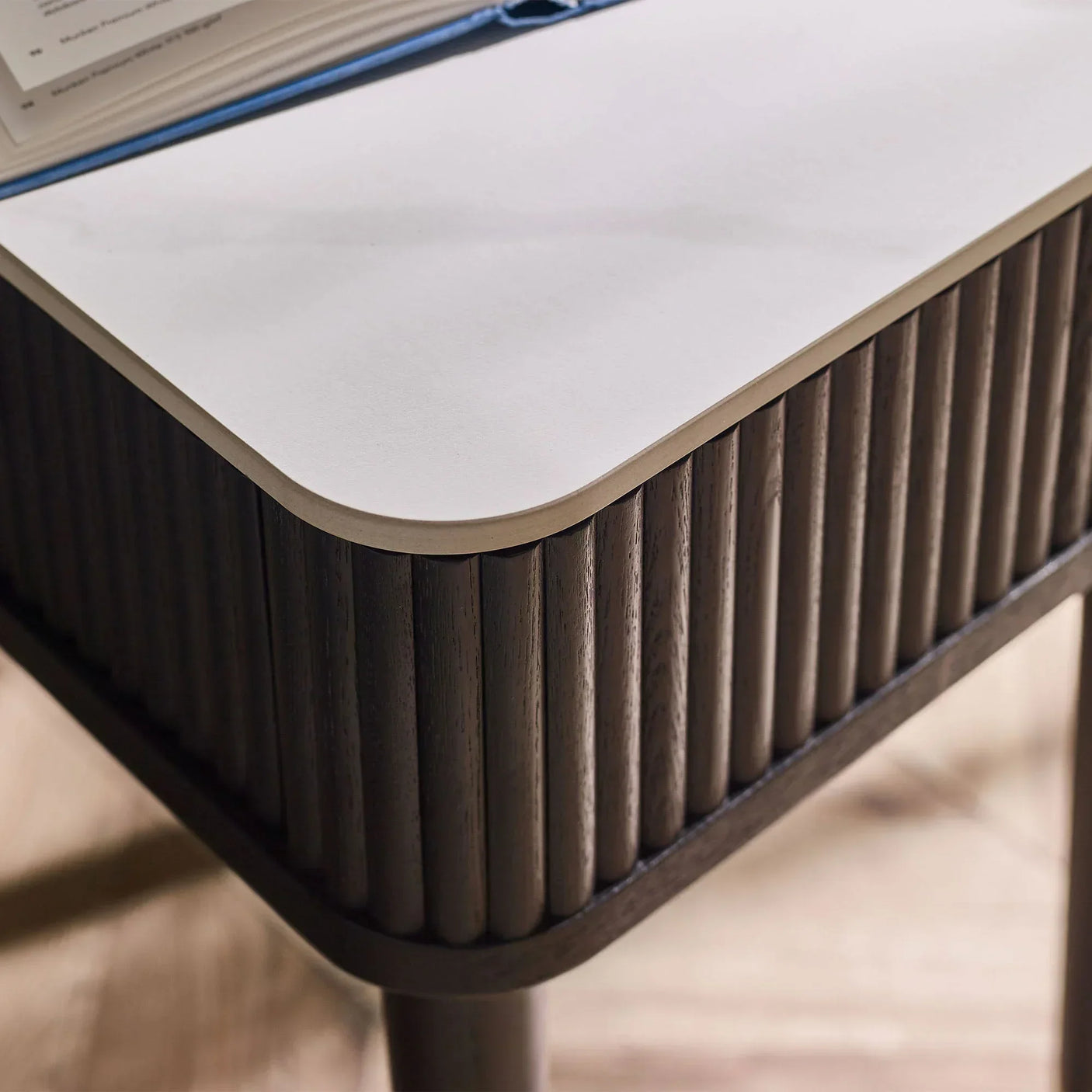 Black fluted lamp table with white stone top and drawer, close corner detail view