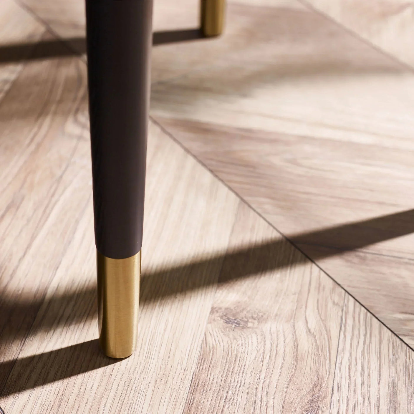 Lamp table leg with matte black finish and brass tip on light wood floor
