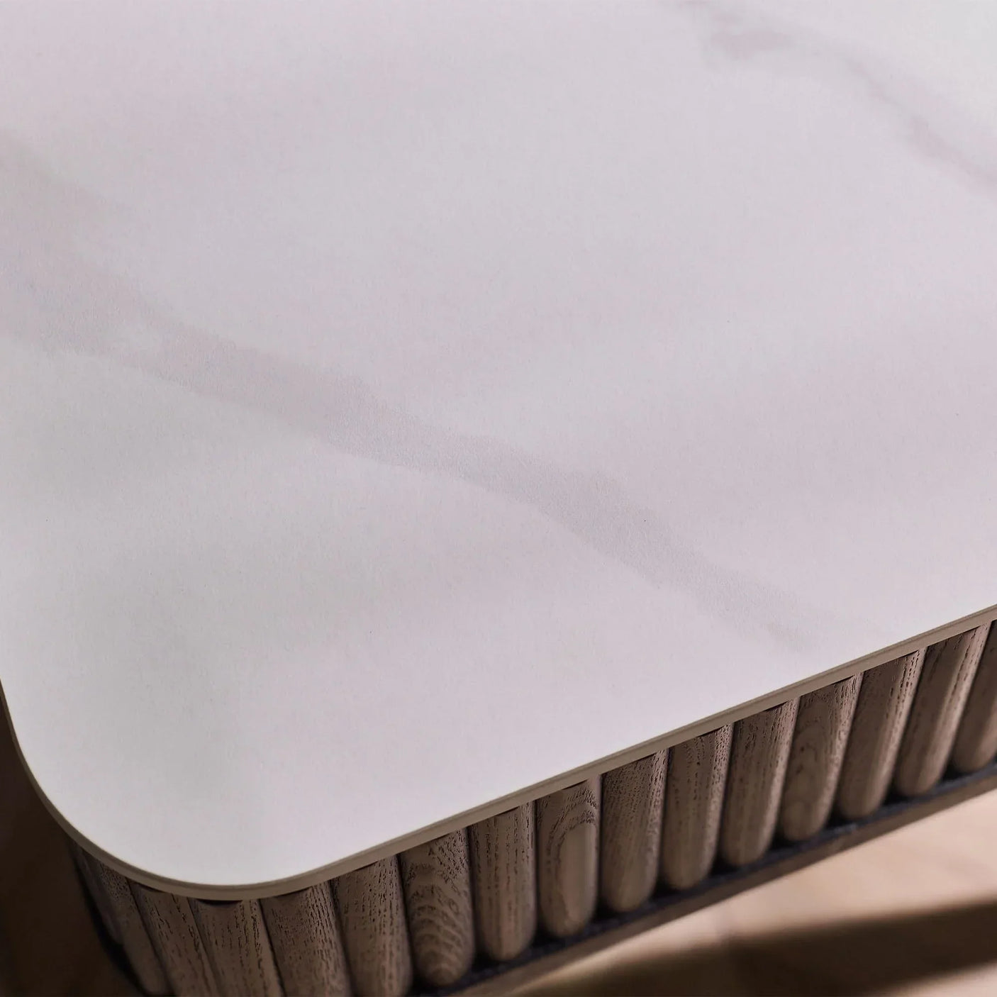 Close up of stone top lamp table with fluted wood detail and soft corner design