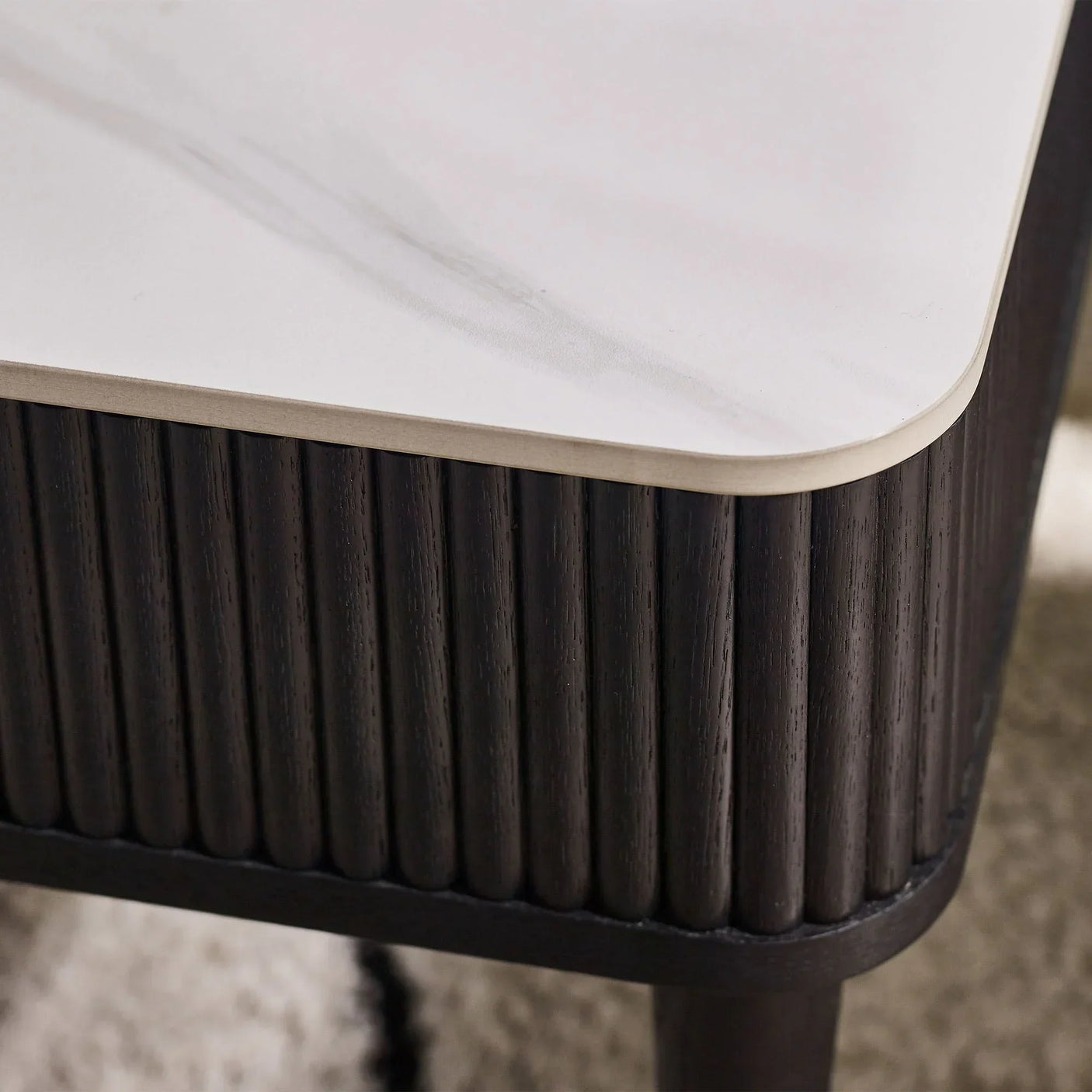 Black fluted coffee table corner with white stone top and vertical wood panel detail