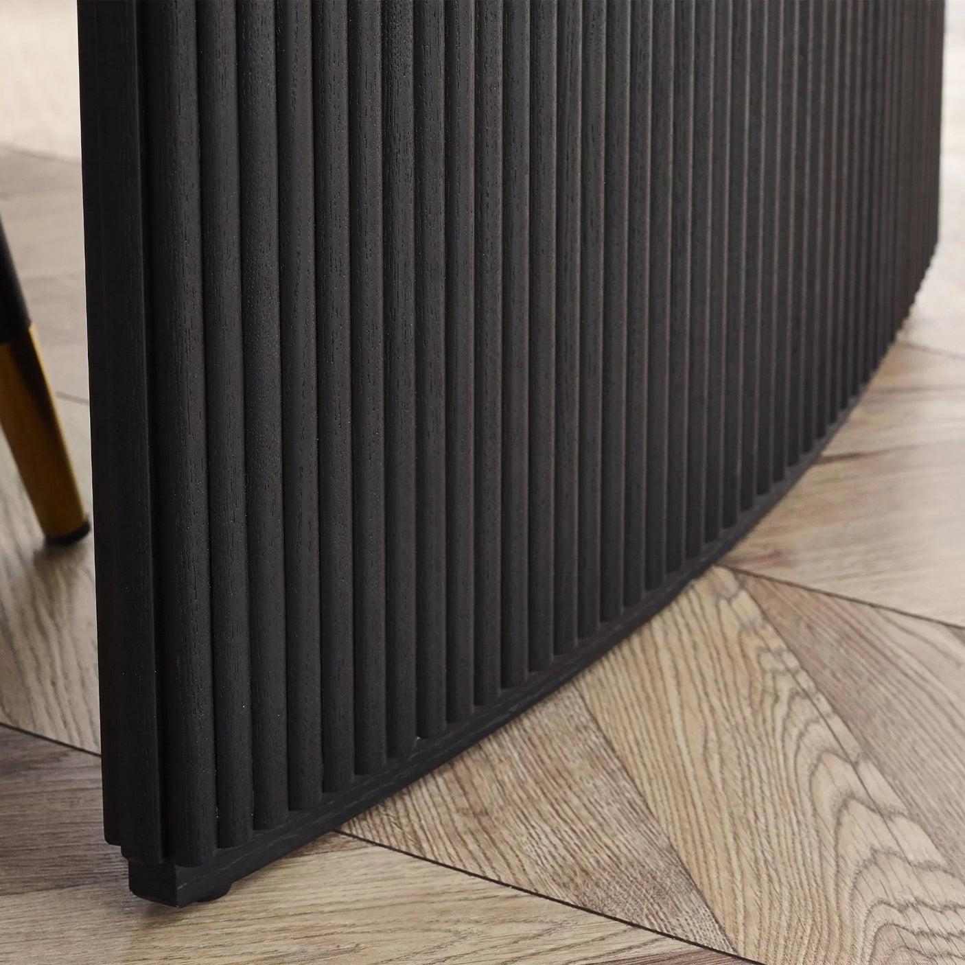 Close-up of black fluted wood leg on extending dining table with parquet floor