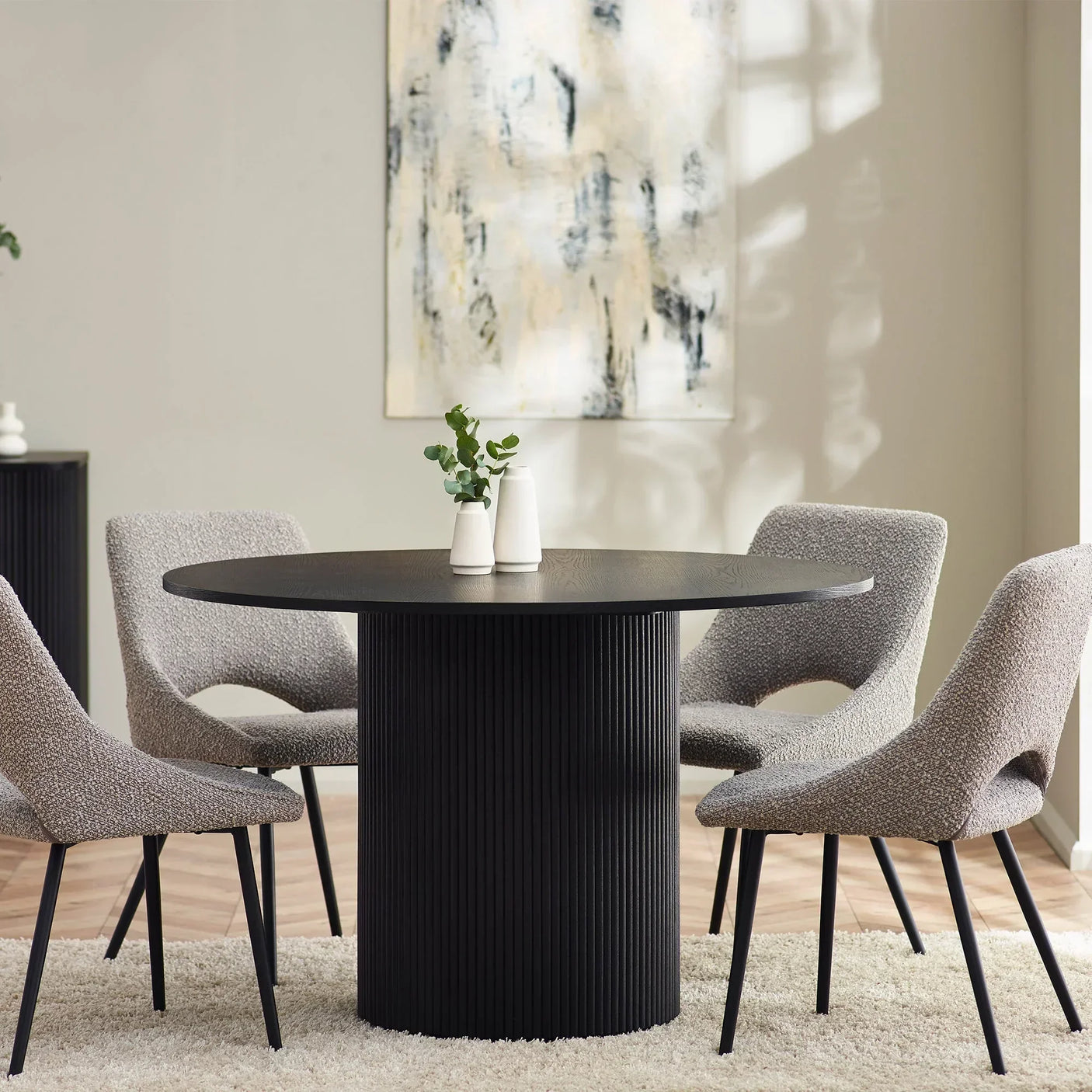 Black fluted round dining table with four grey chairs in a modern dining room