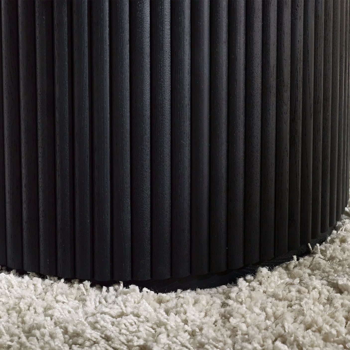 Black fluted round coffee table base detail on cream textured rug