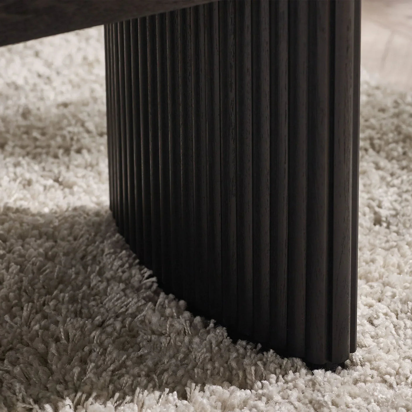 Black fluted compact coffee table leg detail on textured rug