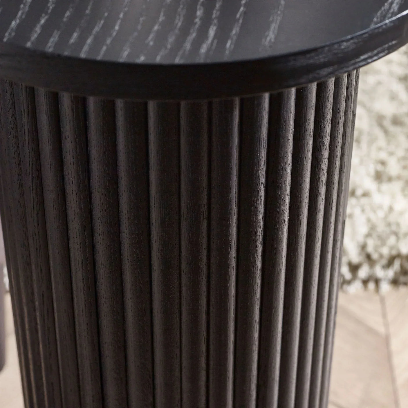 Black fluted drinks table with ribbed cylindrical wood base, close-up of textured detail