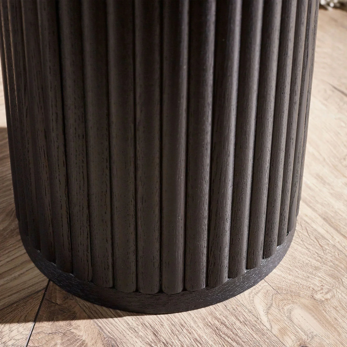 Black fluted drinks table base with ribbed wood detail on light oak floor