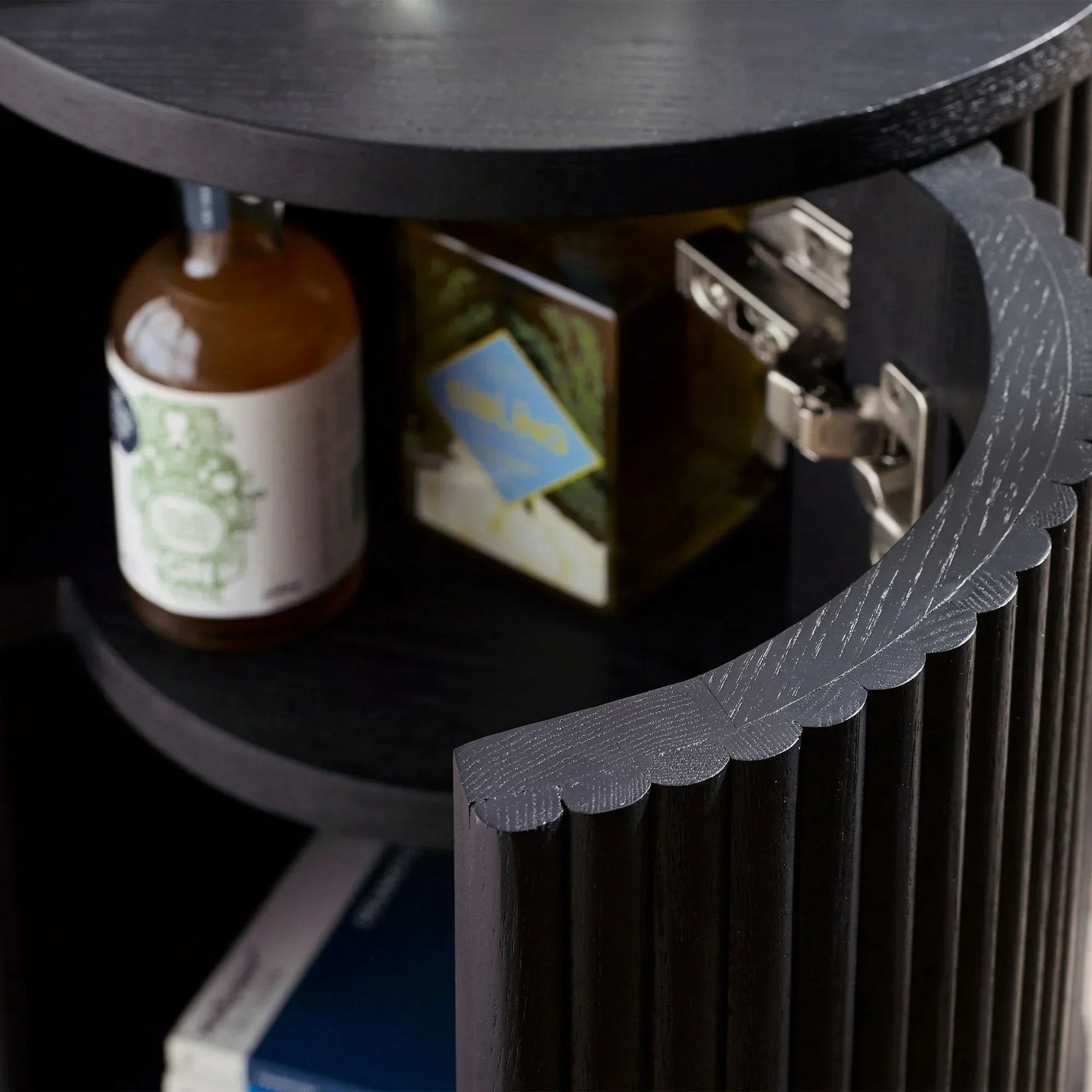 Black fluted side table with open door showing interior shelves and hinge detail