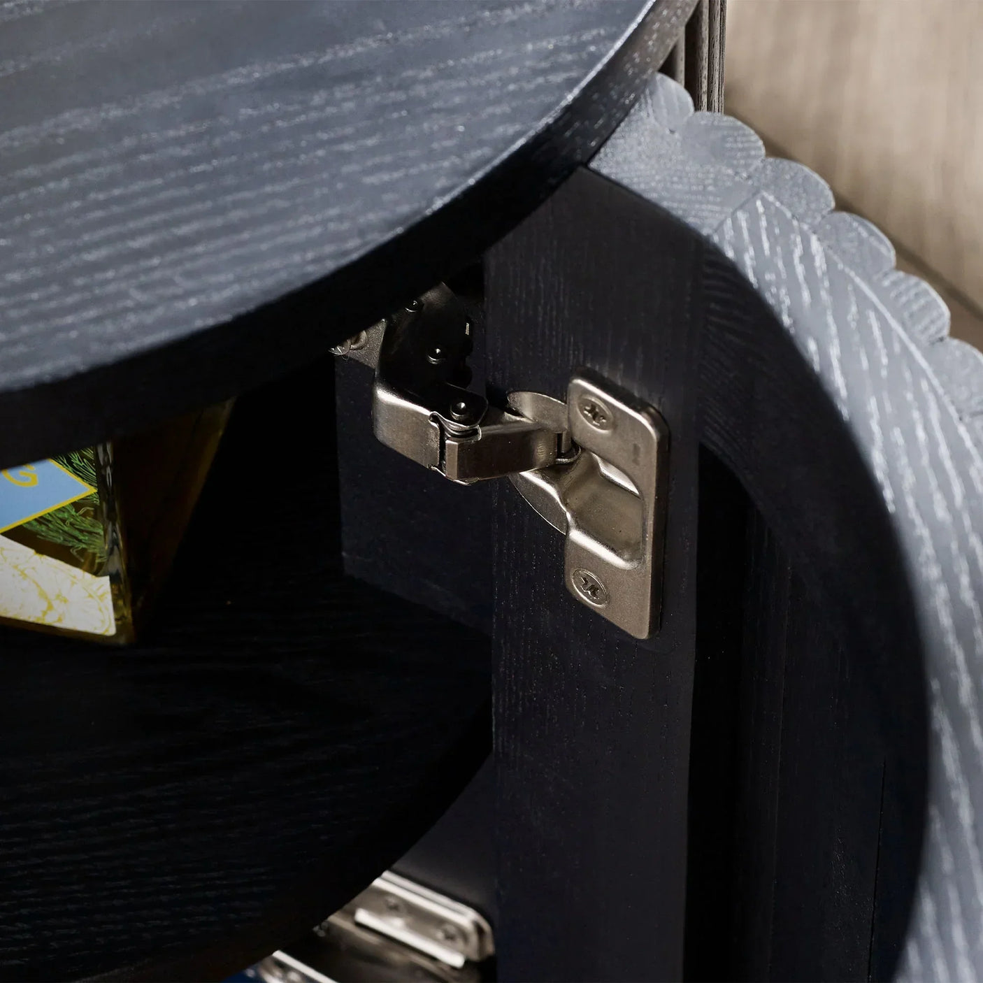Black fluted side table closeup showing metal door hinge and wood grain detail