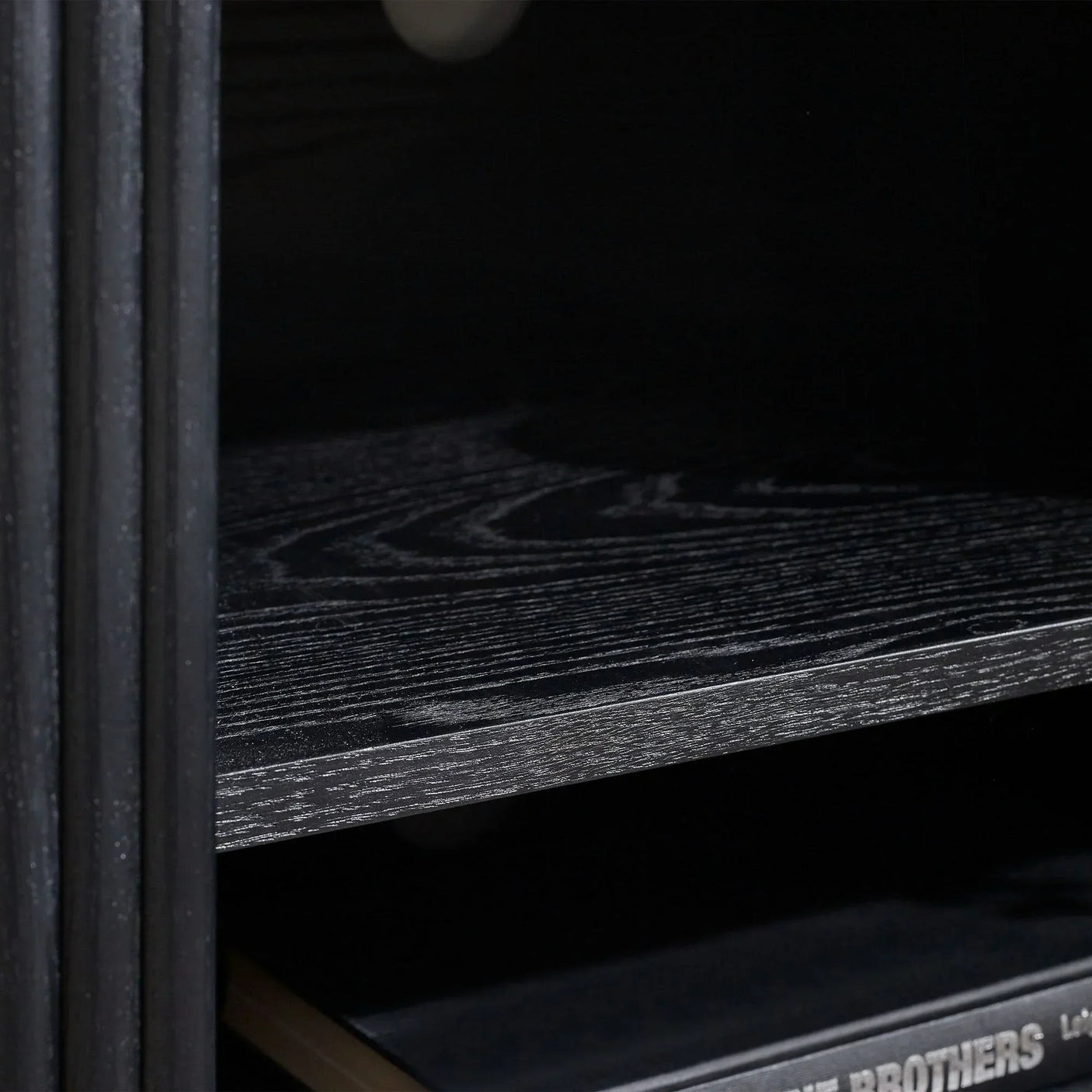 Black fluted TV unit with close-up of wood grain shelf and storage section