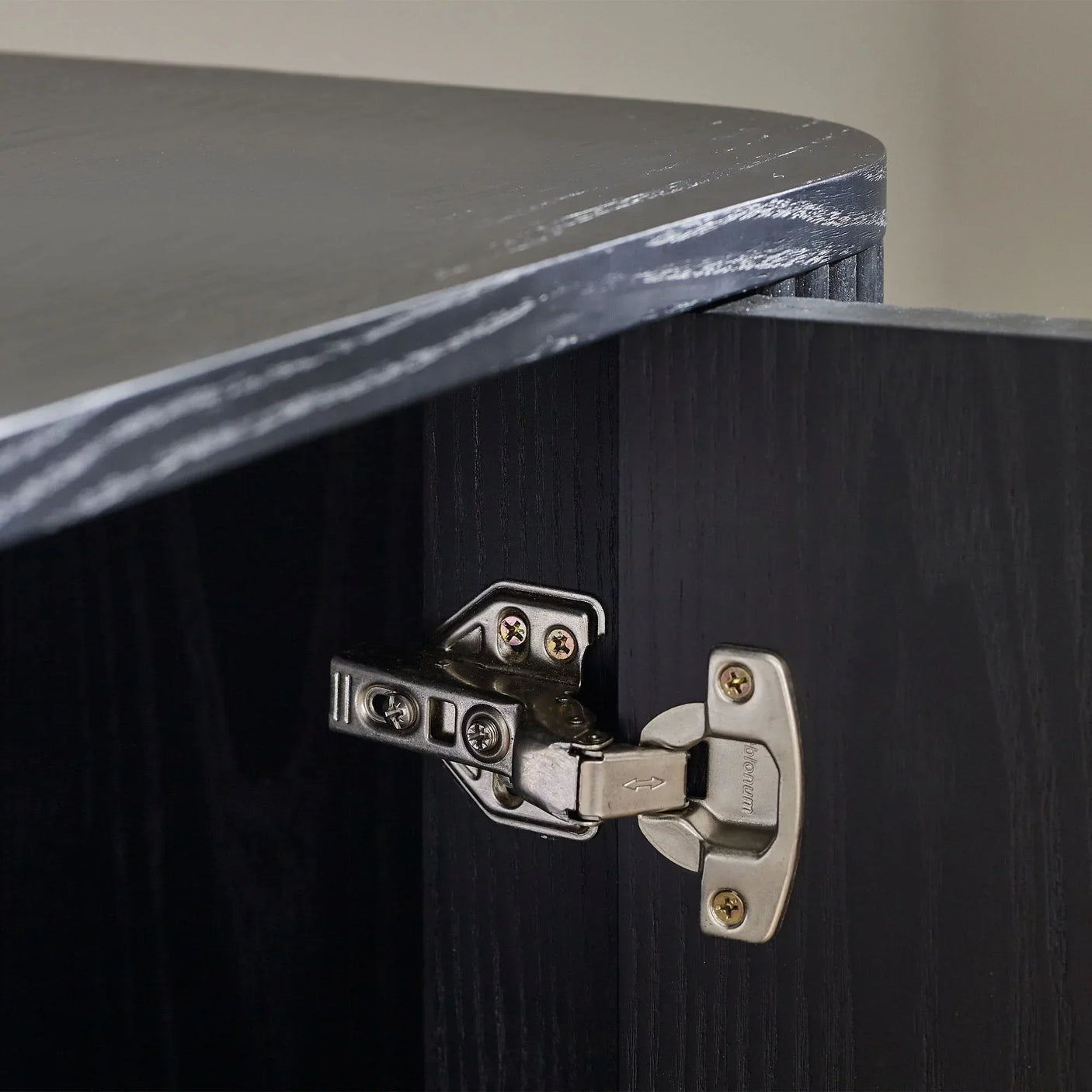 Close-up of black fluted TV unit door hinge and textured wood grain finish