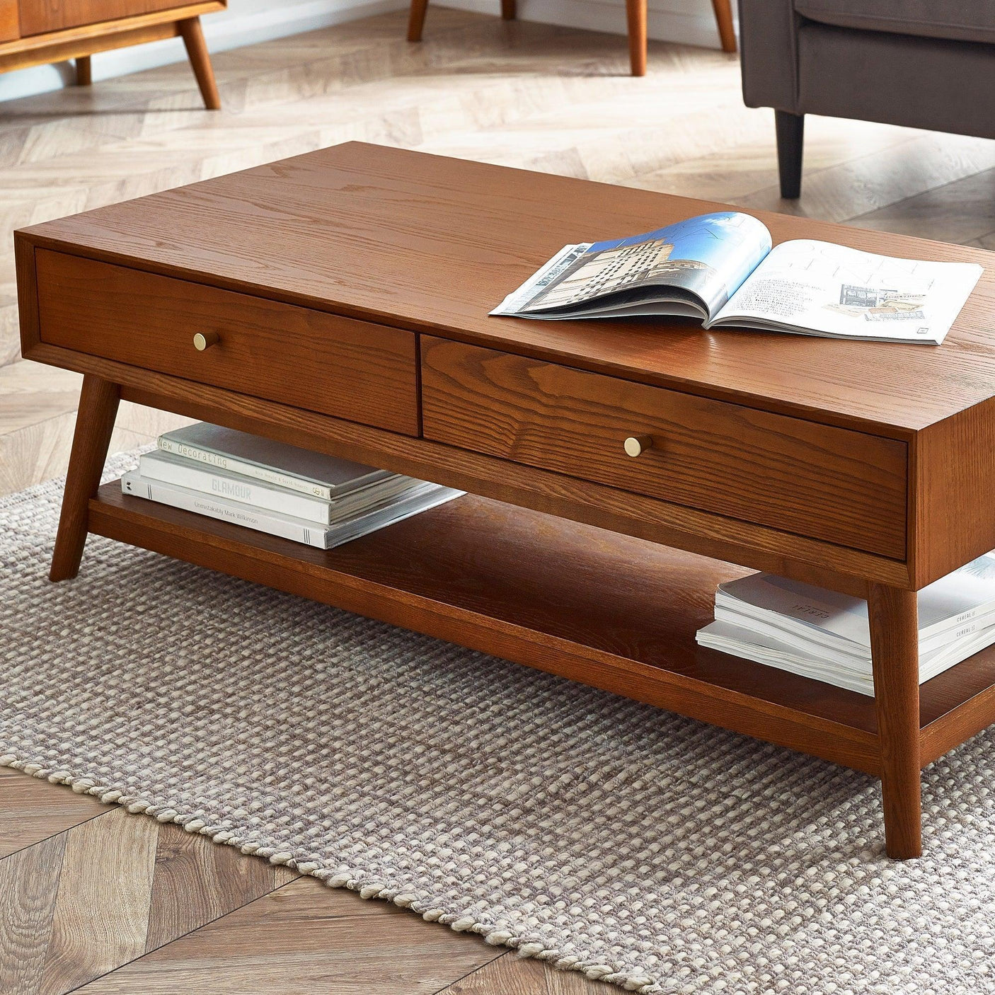 Lowry 2 drawer coffee table in wood finish with shelf, styled on woven rug in living room