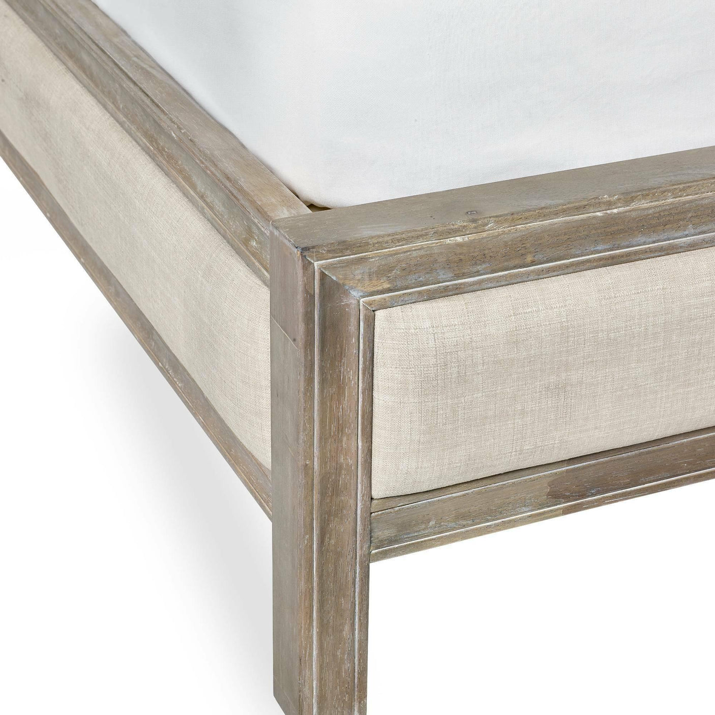 Corner view of wooden bed frame with light fabric upholstery and white mattress