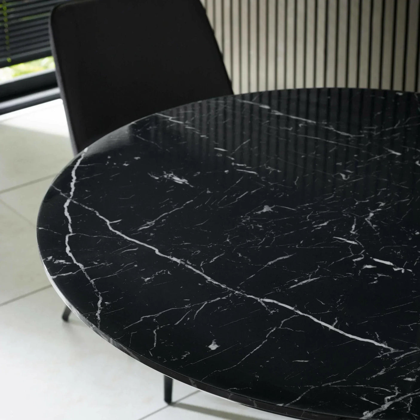Round black marble dining table with white veining and modern chair in contemporary room