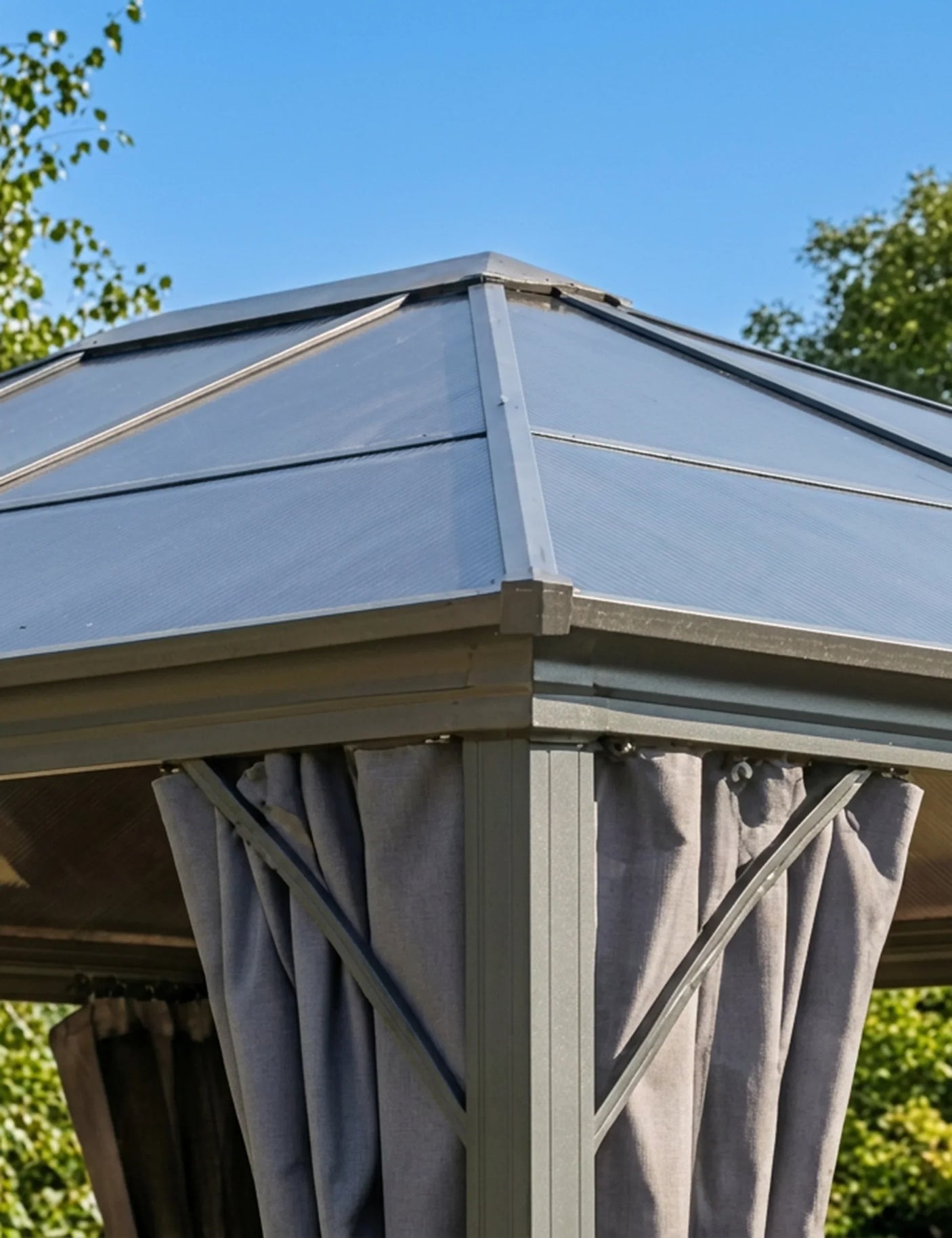Grey metal garden gazebo with fabric curtains and polycarbonate roof