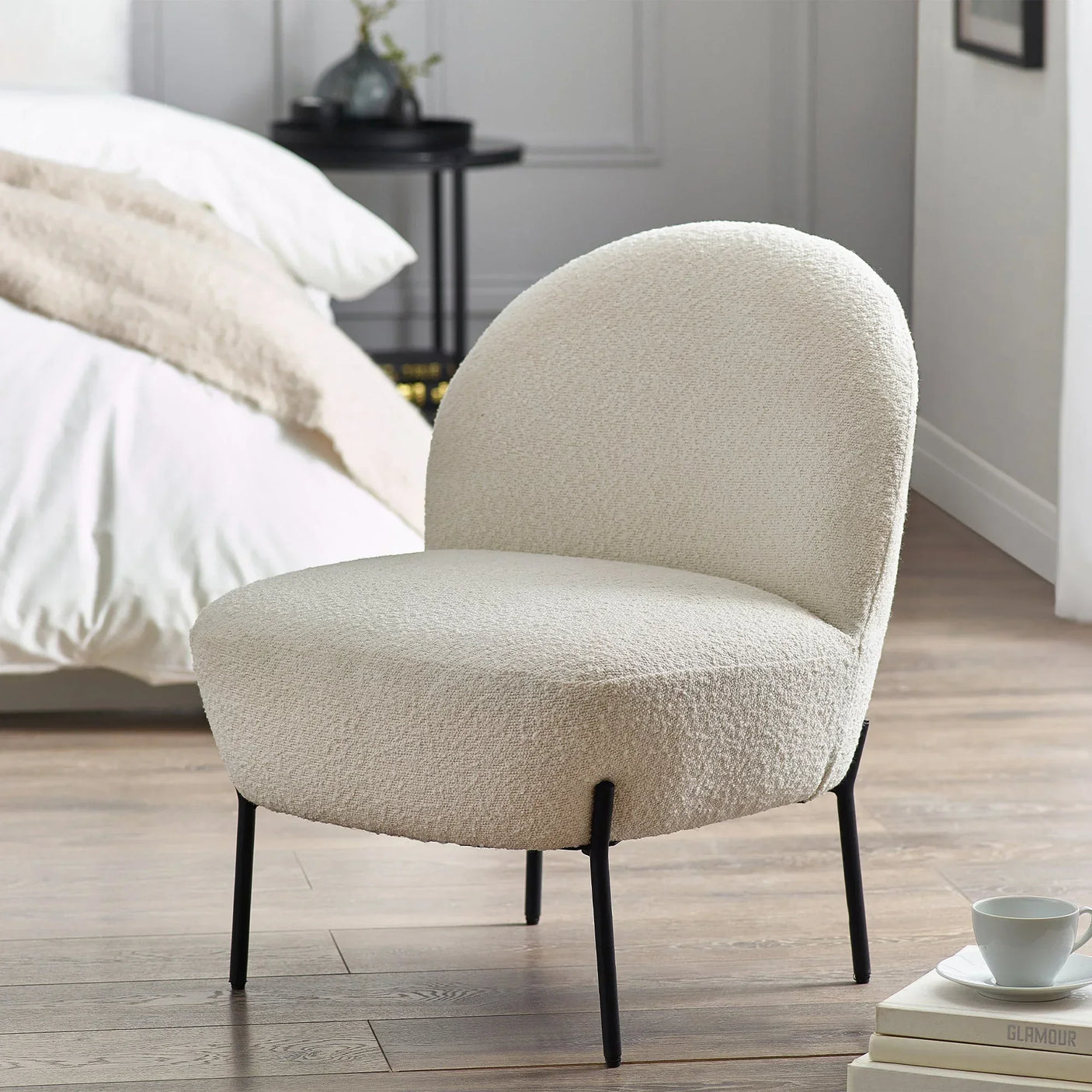 Boucle accent chair with rounded back and black legs in modern bedroom setting