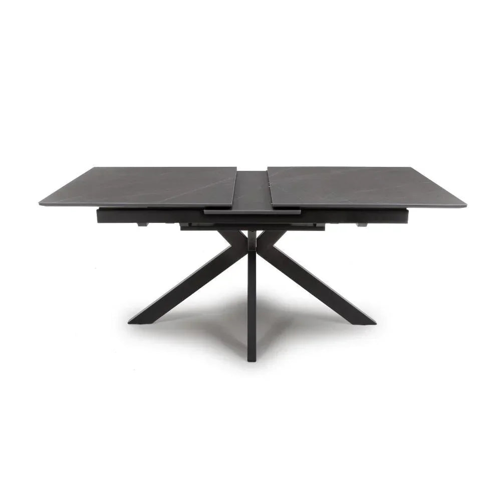 Black extending dining table with ceramic top and angled metal legs, shown extended