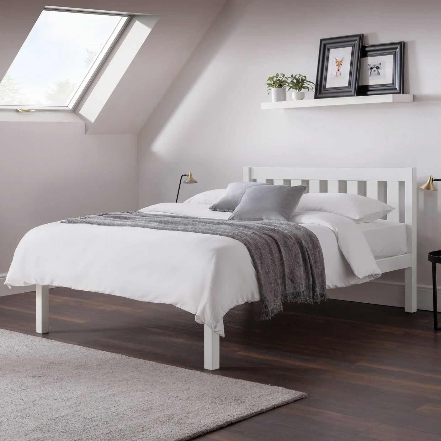 White double bed with slatted headboard, grey throw, and pillows in a modern attic bedroom