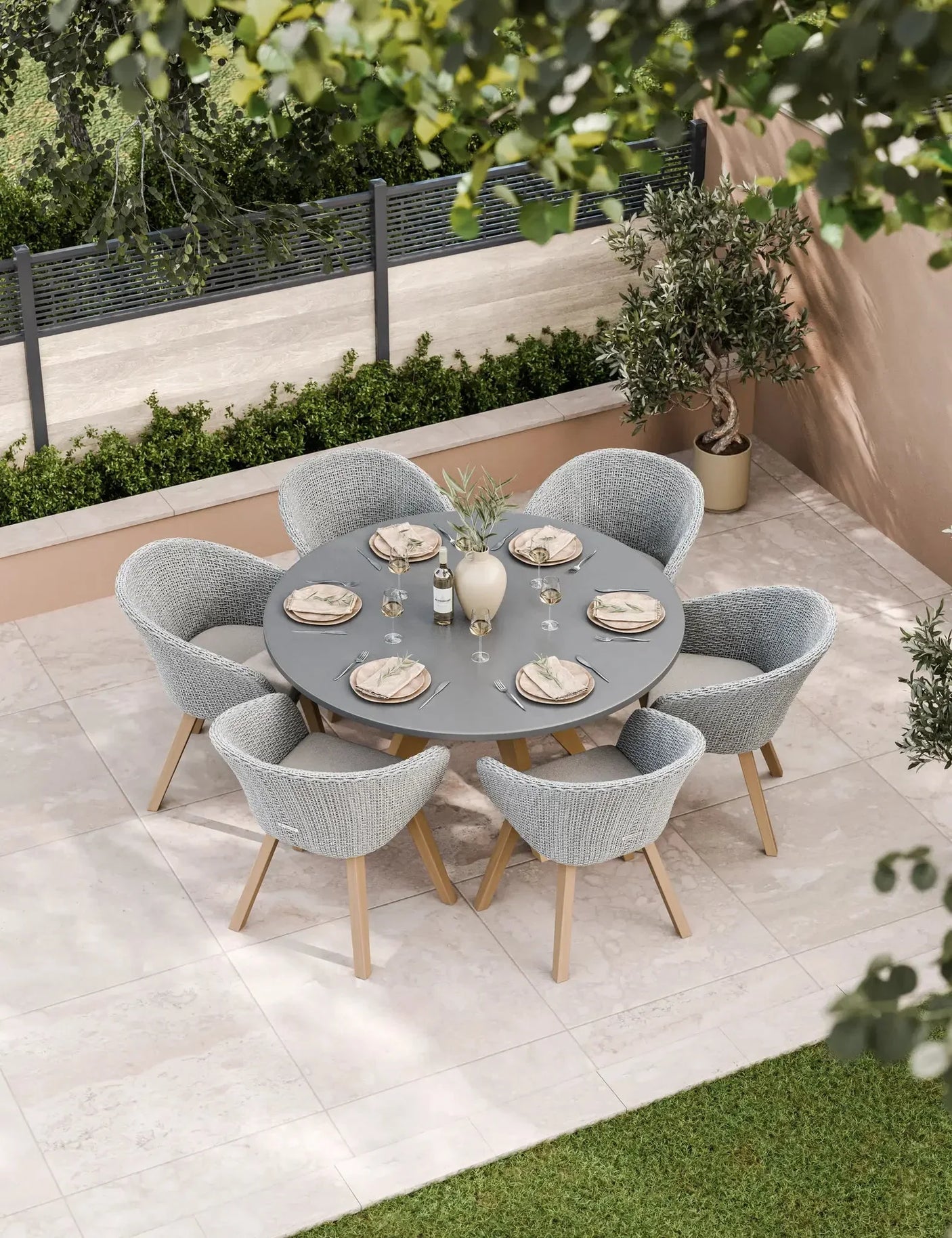 Grey rattan outdoor dining set with round table and six chairs on patio