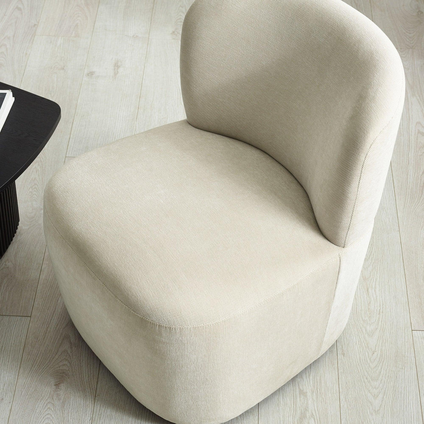 Beige fabric accent chair with curved backrest on light wood flooring