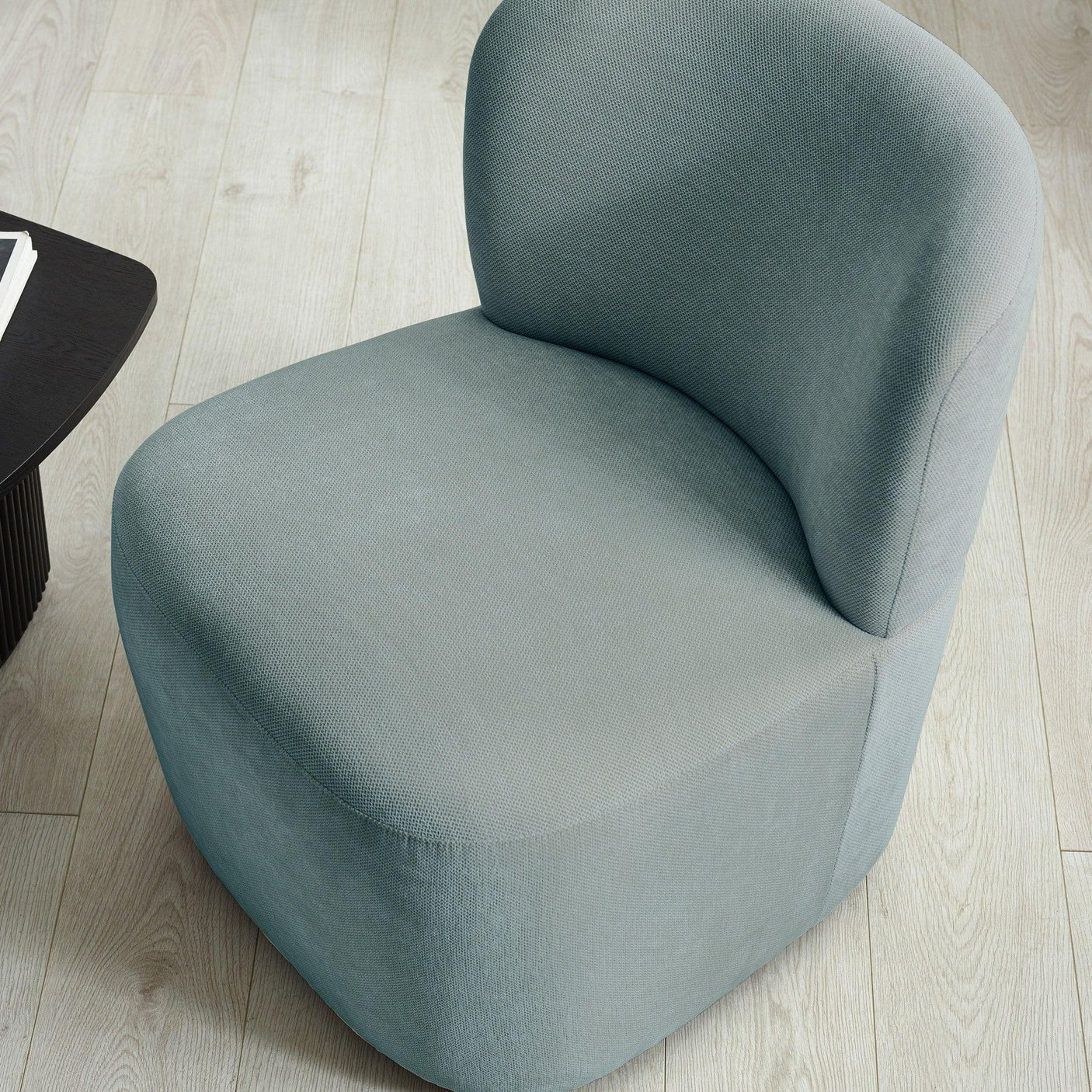 Light grey fabric accent chair with curved backrest on light wood flooring