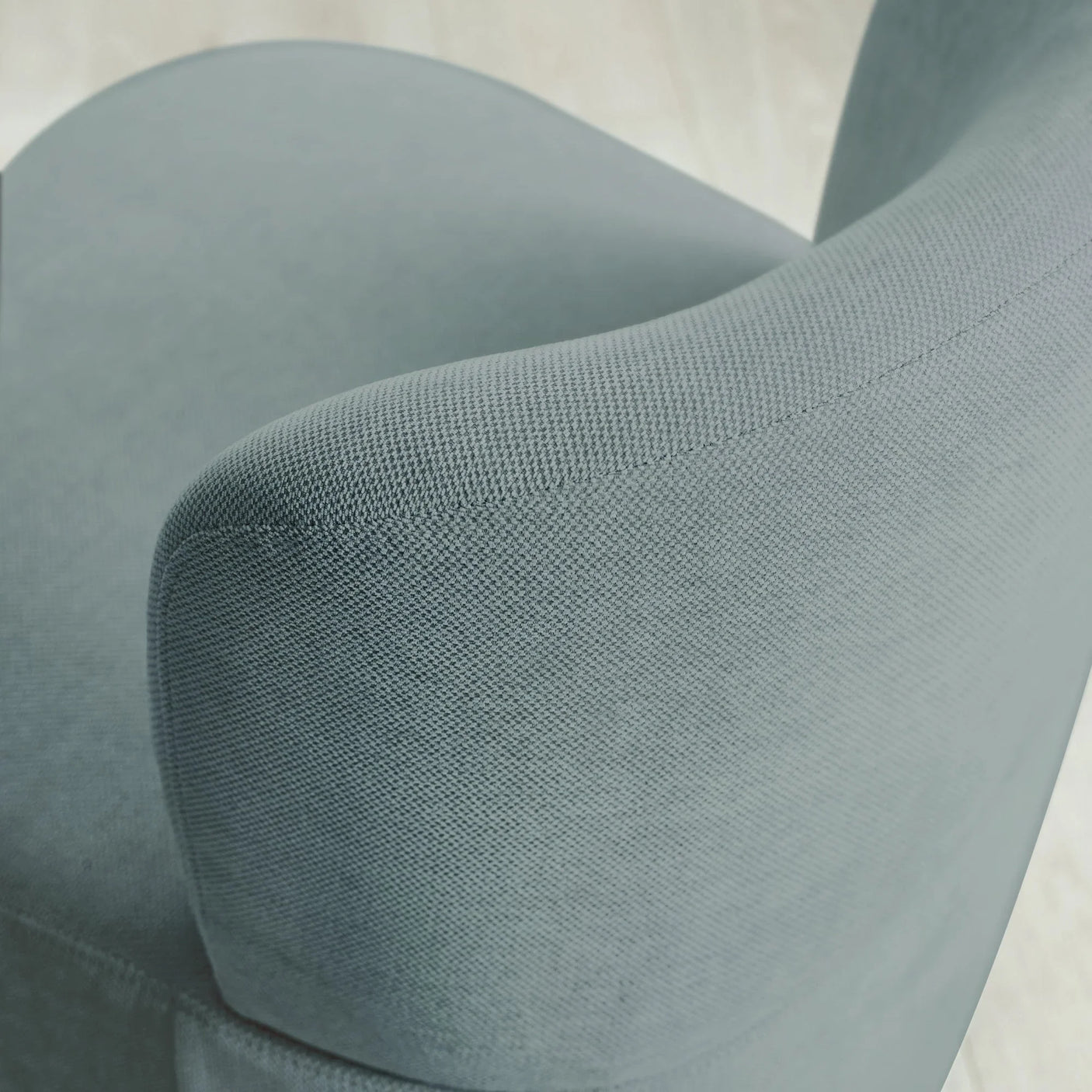 Closeup of grey fabric armchair showing curved armrest and textured upholstery