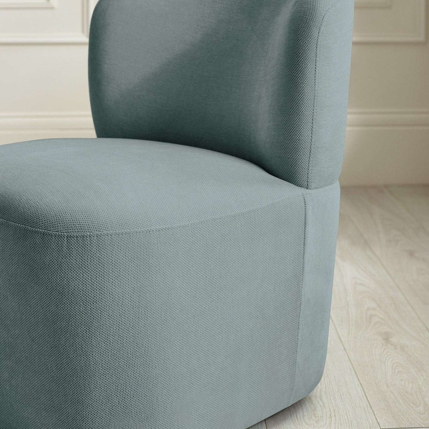Close-up of modern upholstered accent chair in light blue fabric on wooden flooring
