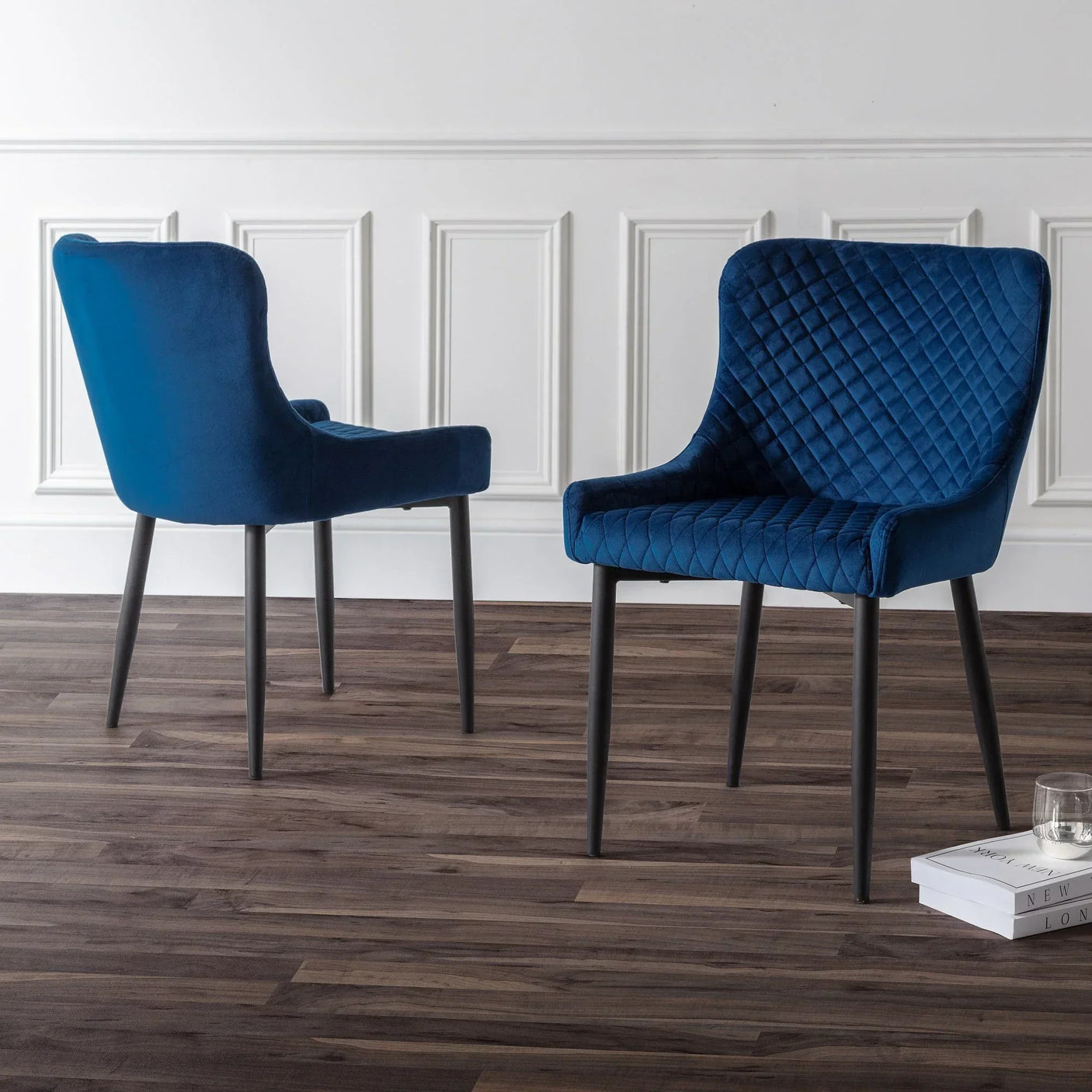 Blue velvet dining chairs with quilted backrest on wood floor in modern dining room