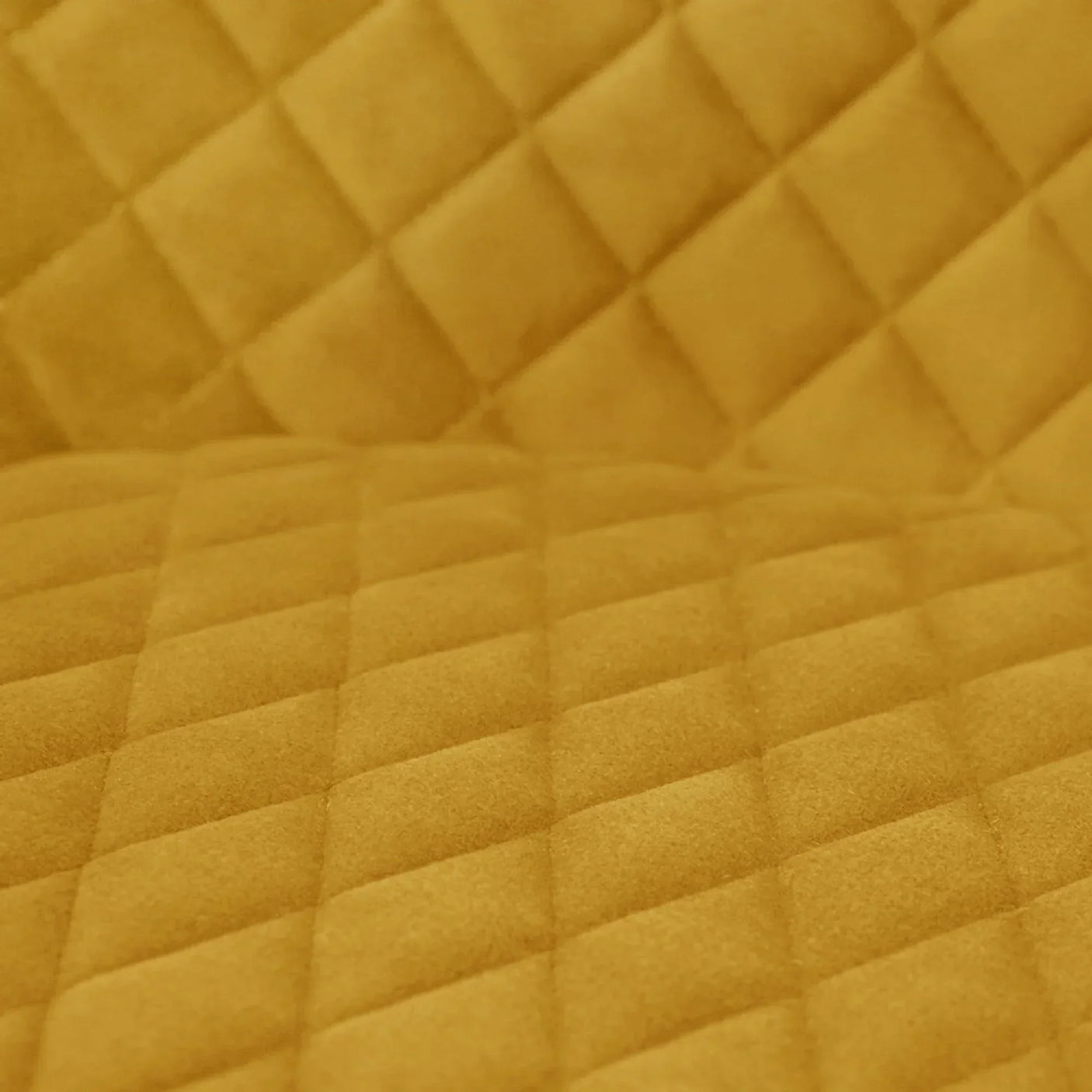 Close-up of mustard velvet dining chair upholstery with diamond quilted pattern