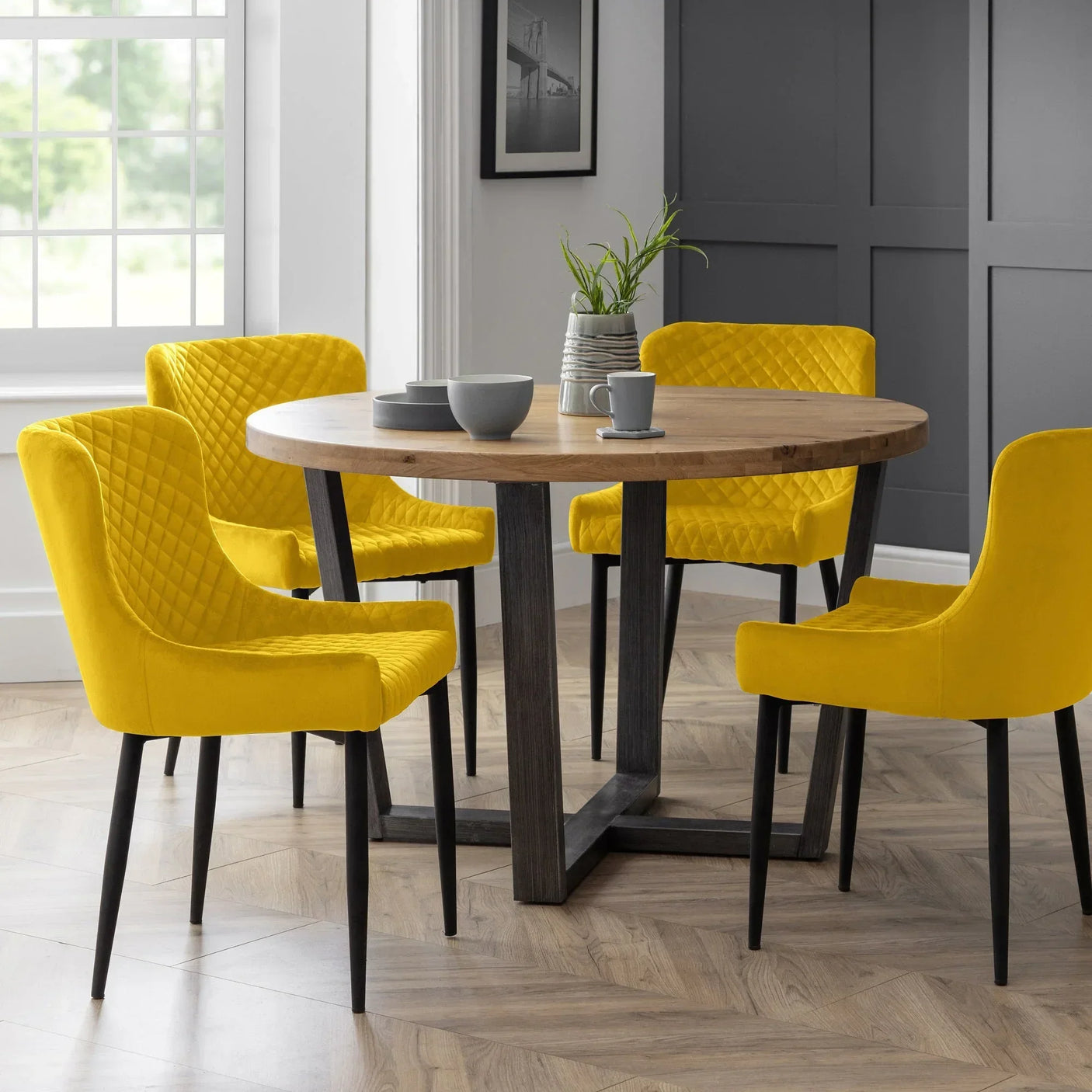 Mustard velvet dining chairs around round wooden table in modern dining room setting