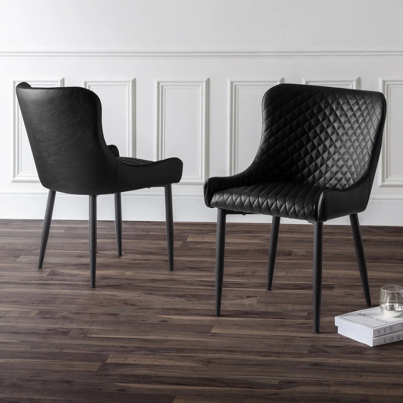 Black faux leather dining chairs with quilted seat detail on wood floor