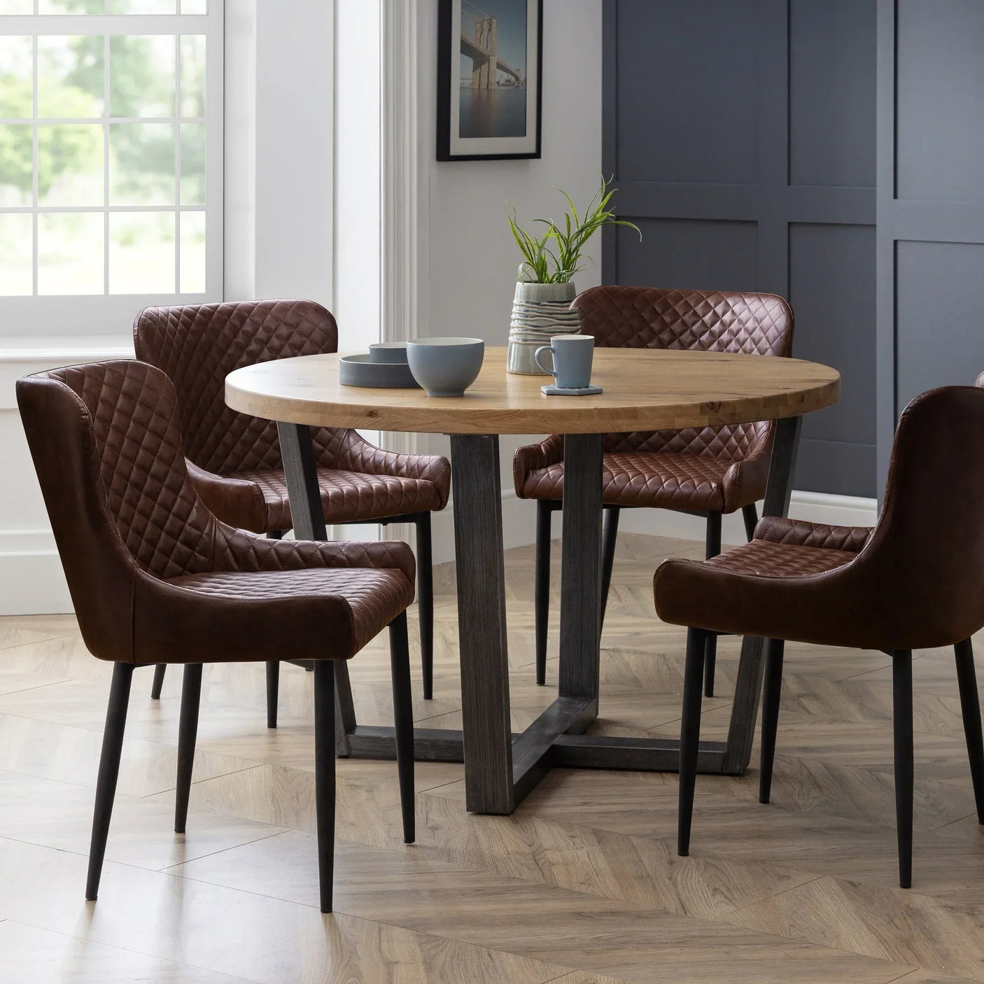 Brown faux leather dining chairs with diamond stitching around round wood table in modern dining room