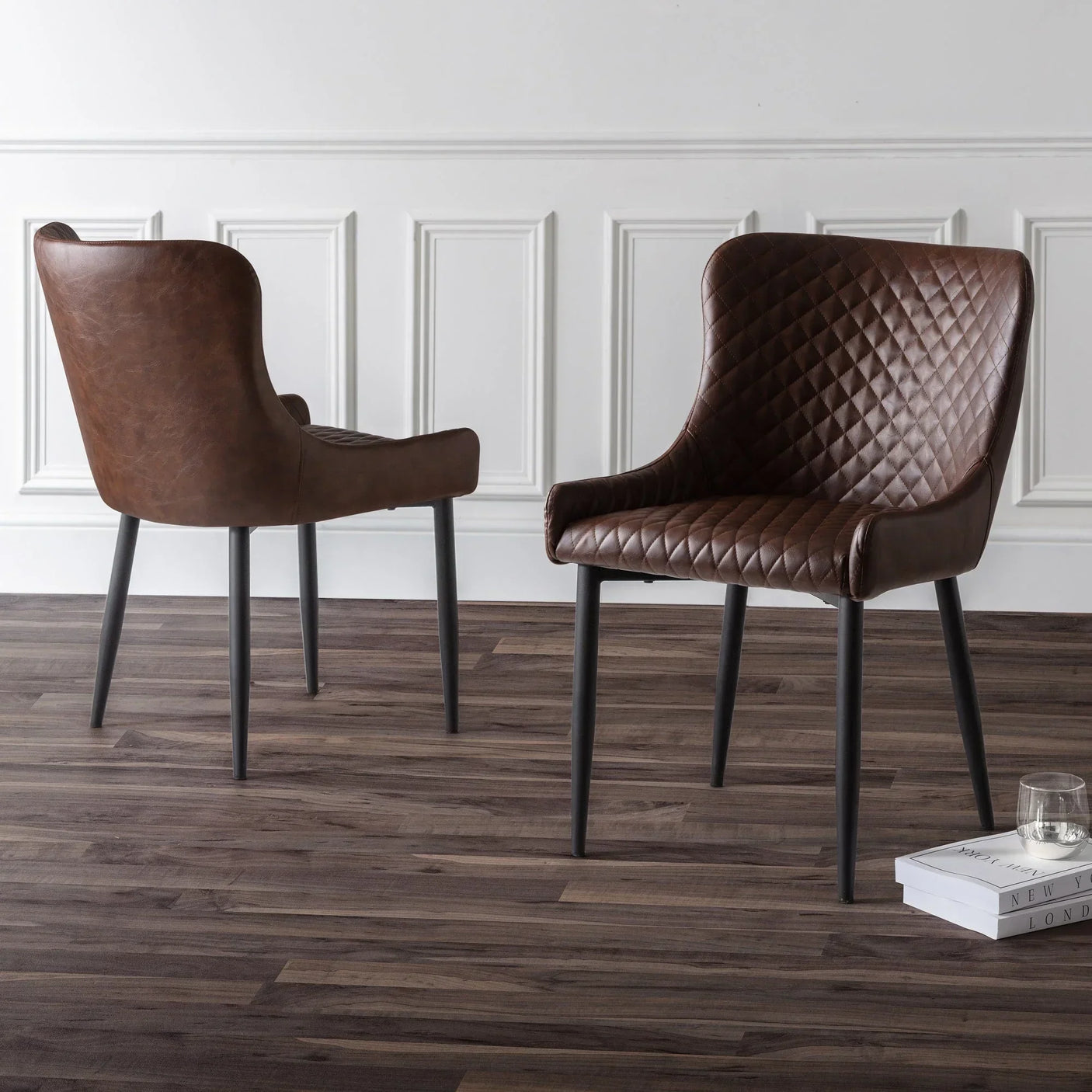Brown faux leather dining chairs with quilted seat and black legs on wooden floor
